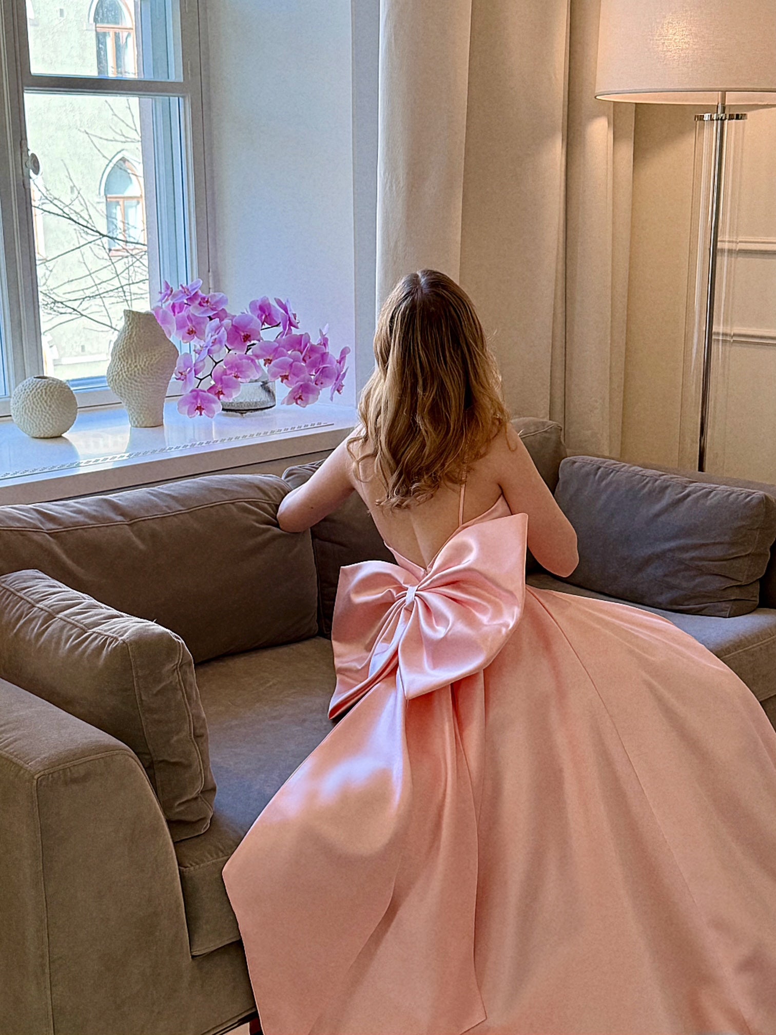 Vaaleanpunainen vanhojentanssimekko isolla rusetilla, lähikuva takaa.