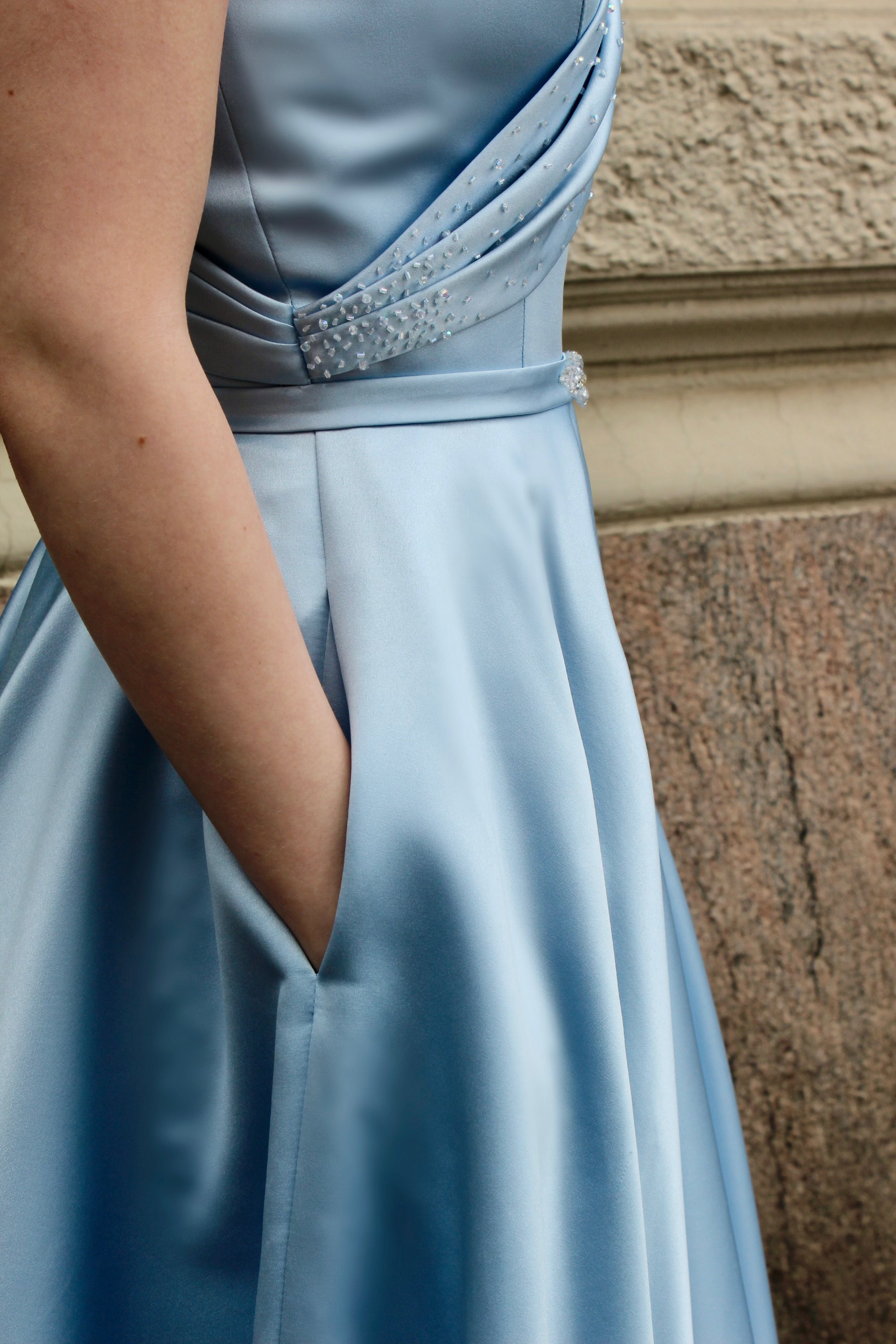 Vaaleansininen yksolkaiminen vanhojentanssimekko satiinista, lähikuva sivusta.