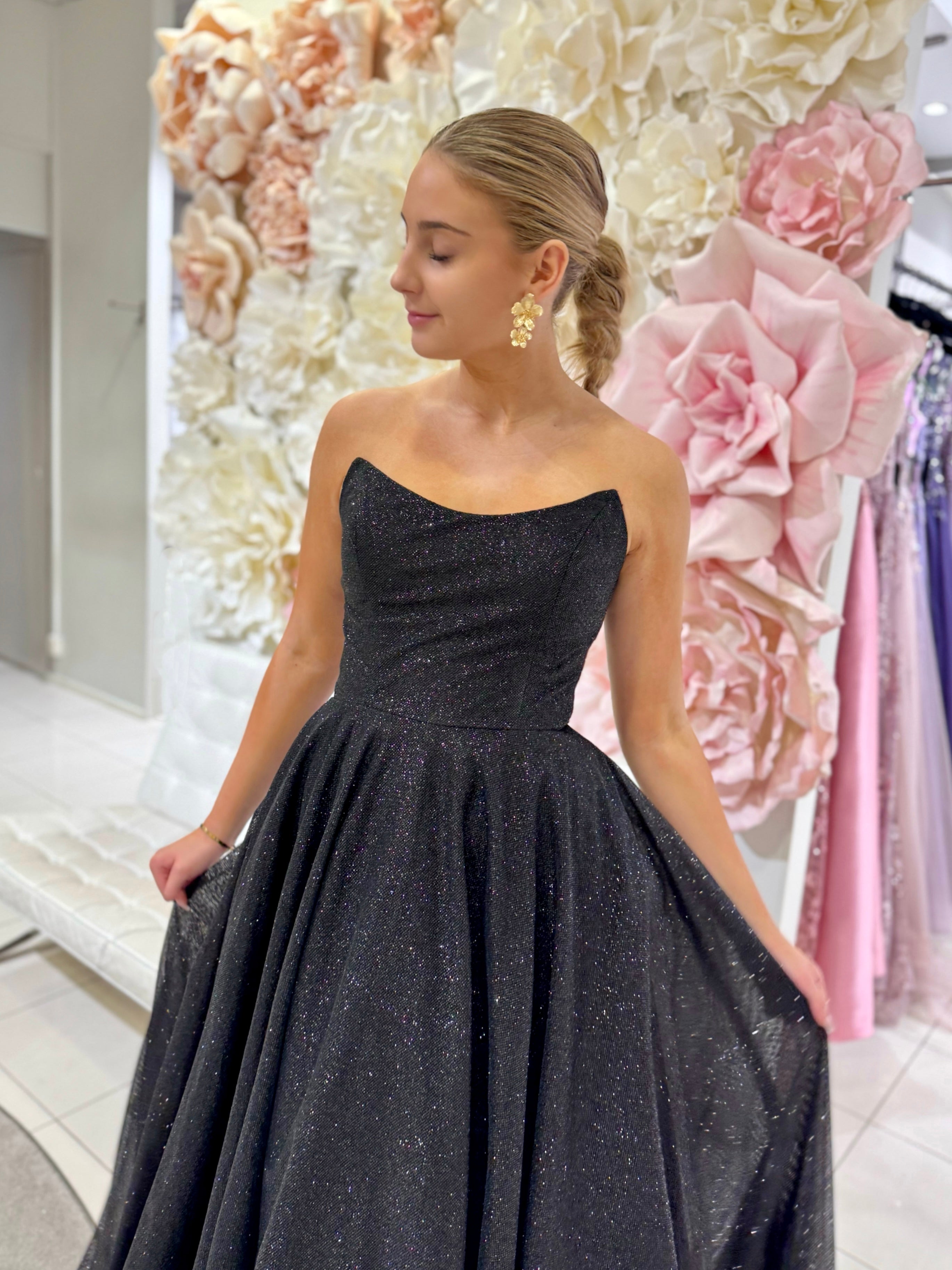 Musta olkaimeton vanhojentanssimekko kimaltavalla kankaalla.