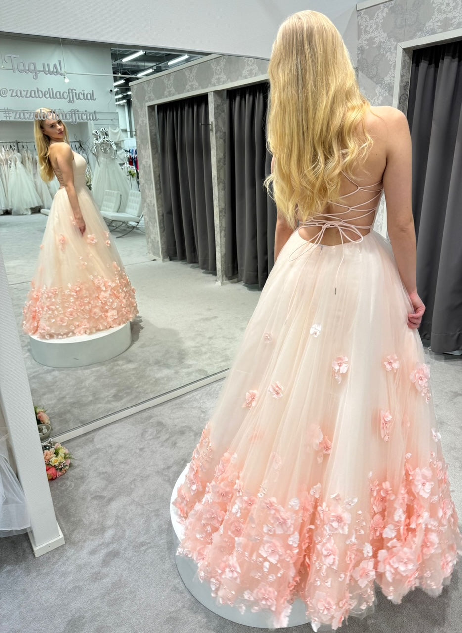 Vaaleanpunainen vanhojentanssimekko 3D kukkakoristein ja avoimella selällä, ilmava helma laskeutuu kauniisti, takaa.