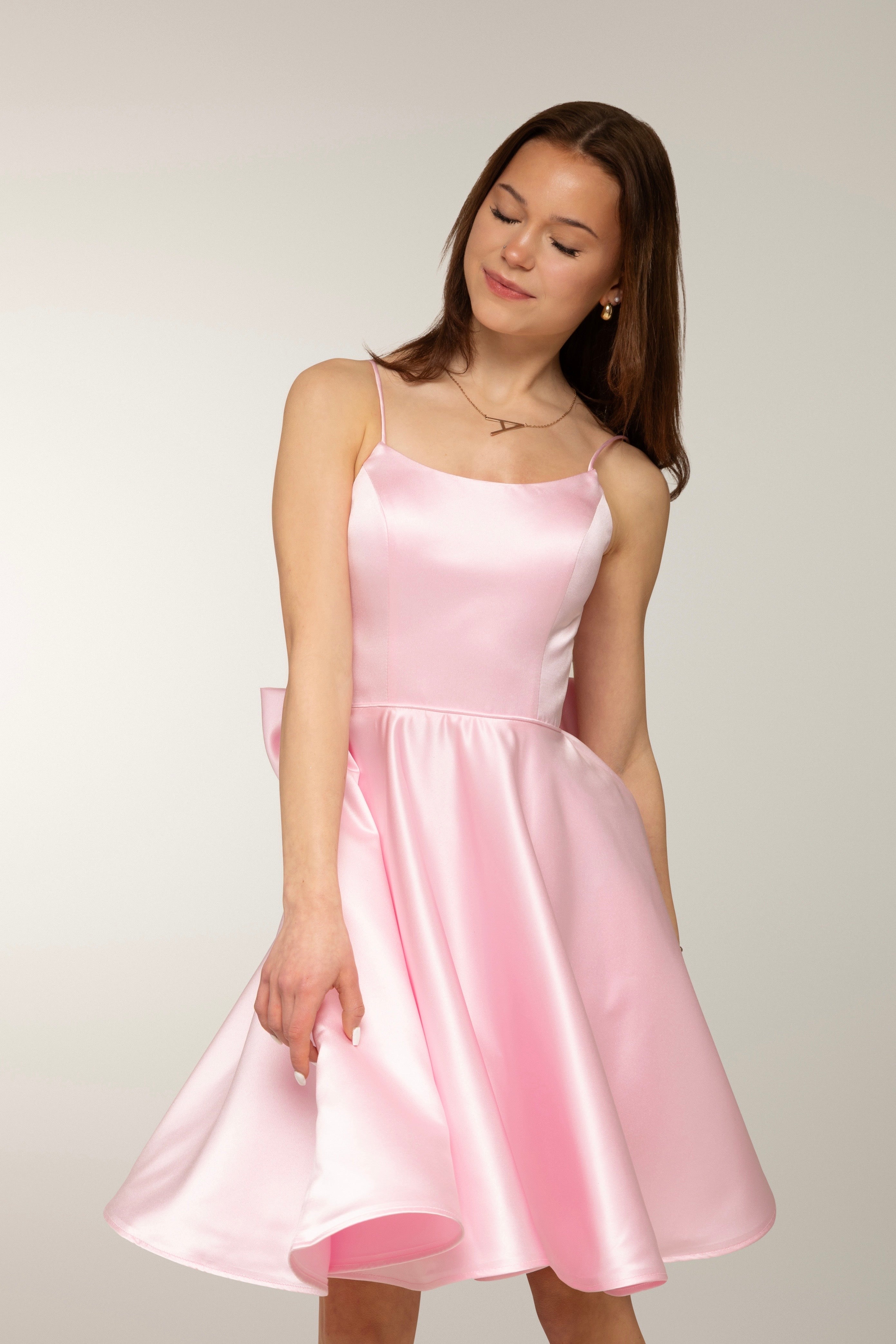 Vaaleanpunainen satiininen rippimekko näyttävällä rusetilla.