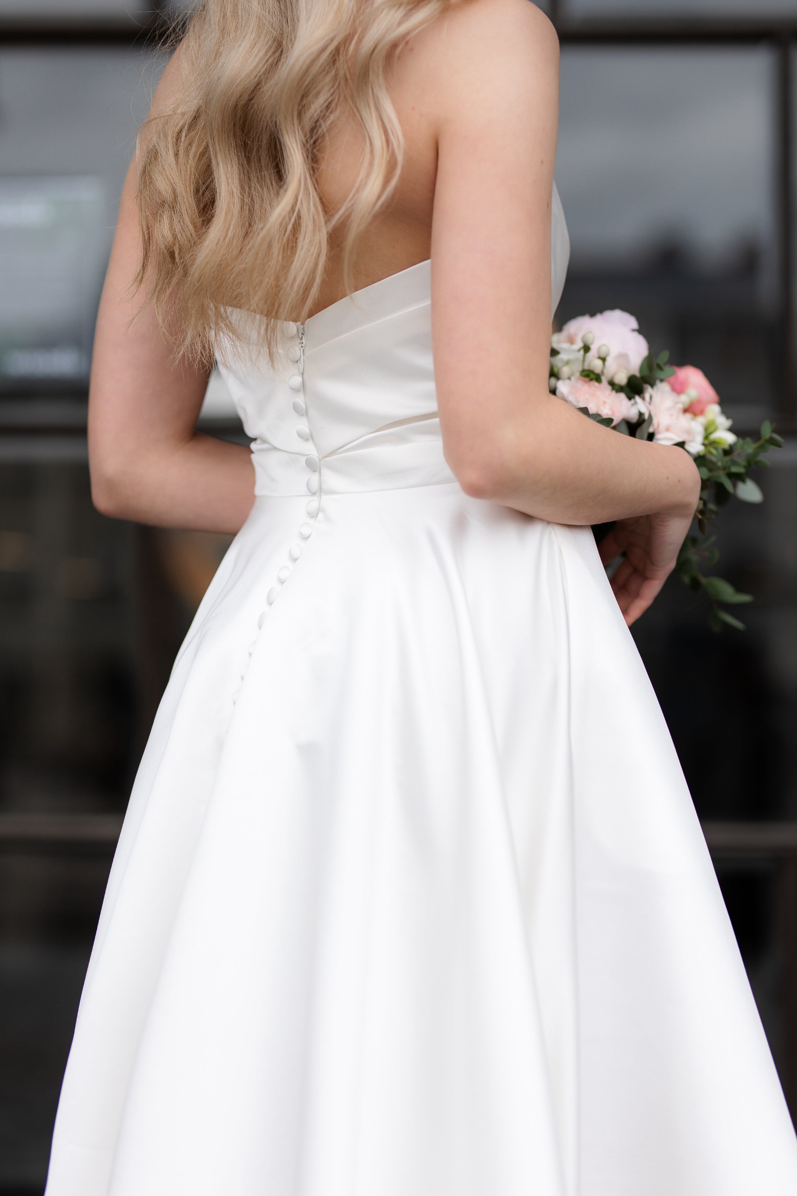 Olkaimeton satiininen häämekko klassisella A-linjaisella leikkauksella, takaa.