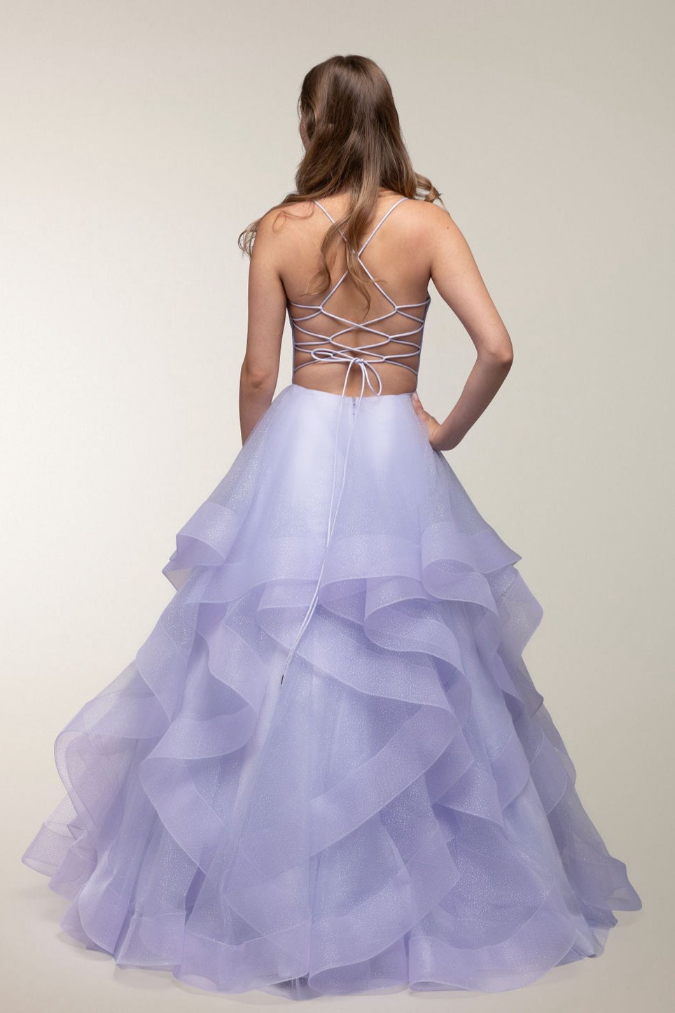 Violetti vanhojentanssimekko kimaltavalla röyhelöhelmalla ja avoimella selällä, takaa.