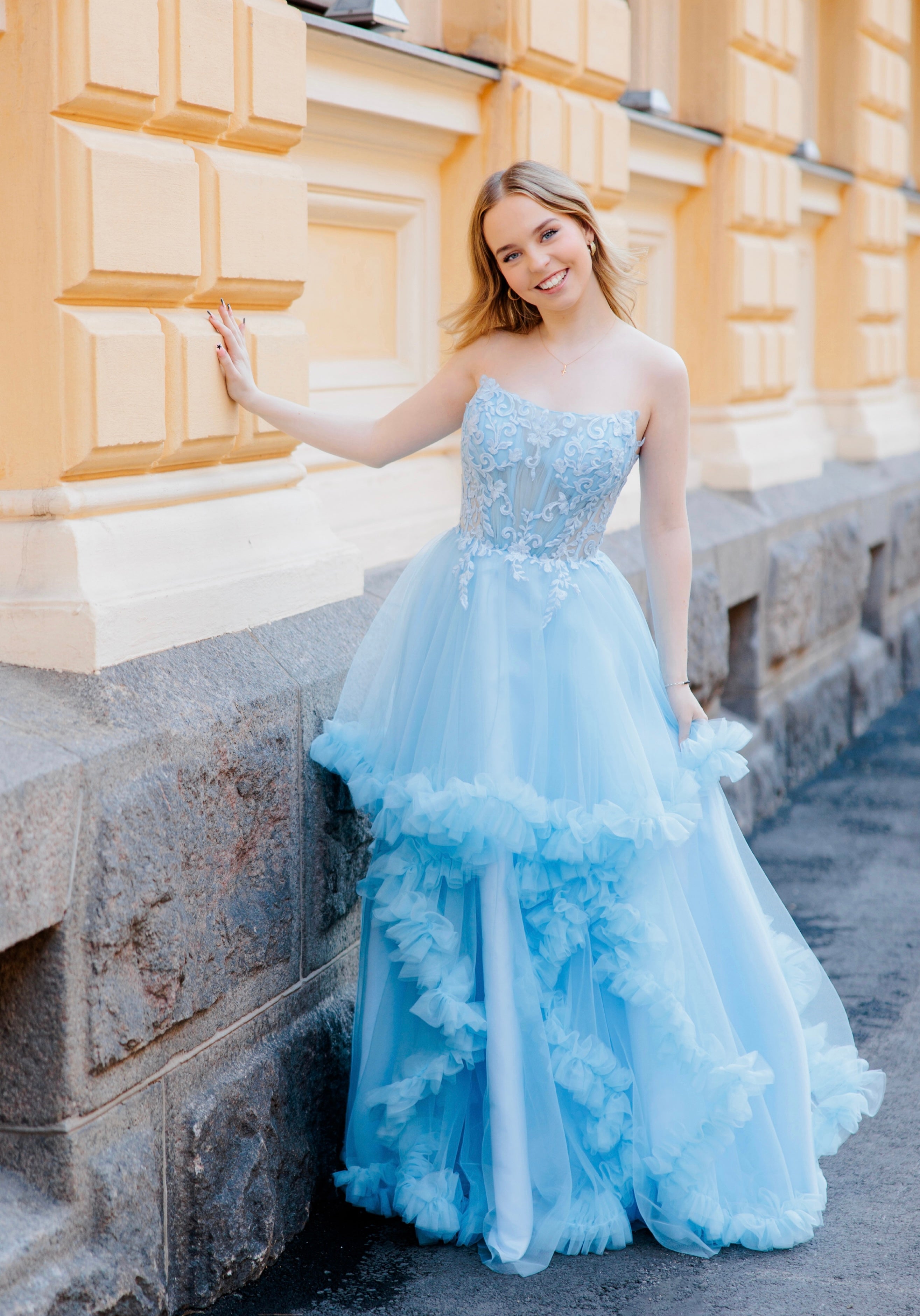 Olkaimeton vaaleansininen röyhelähelmainen vanhojentanssimekko, edestä kuvattu.