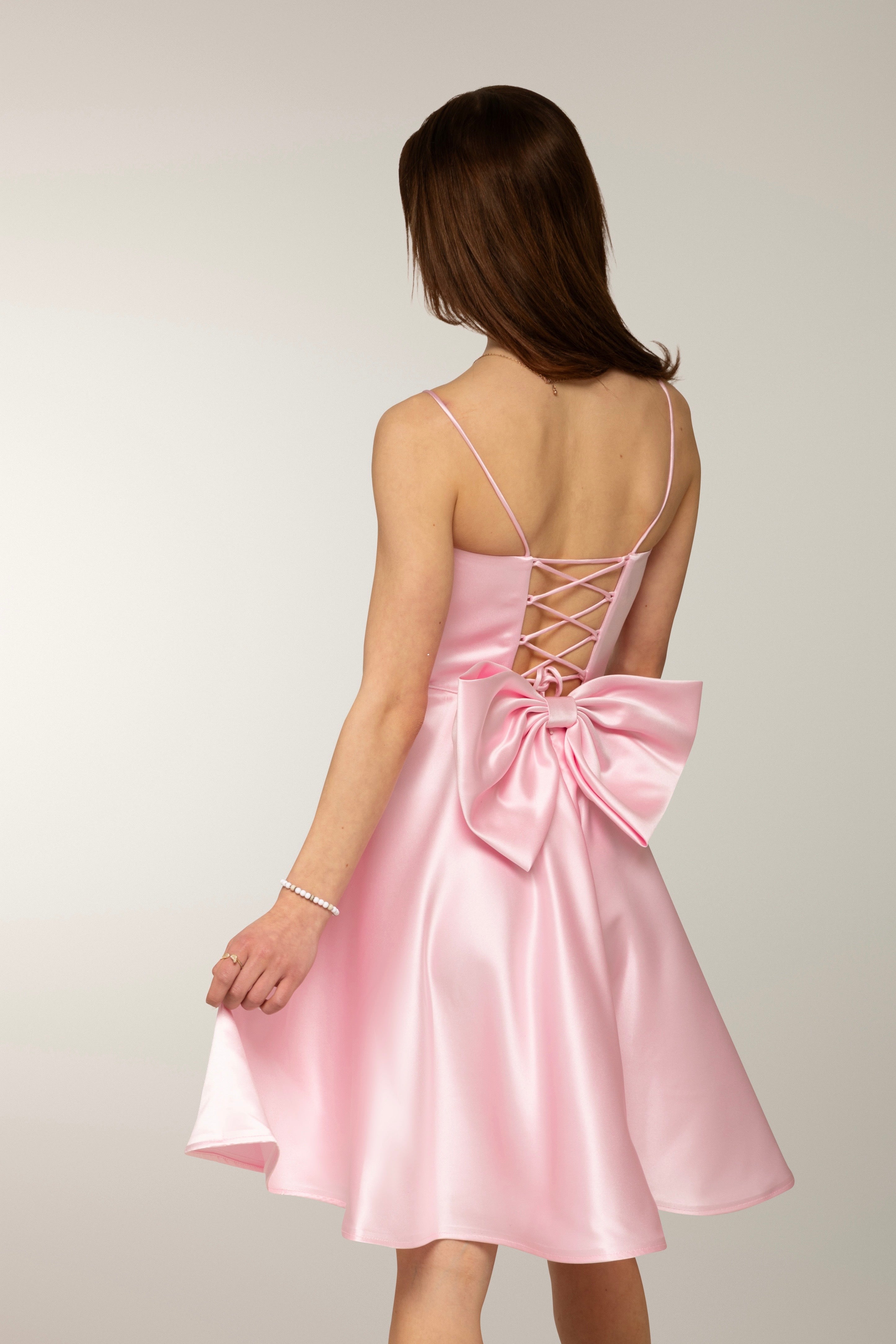Vaaleanpunainen satiininen rippimekko näyttävällä rusetilla.