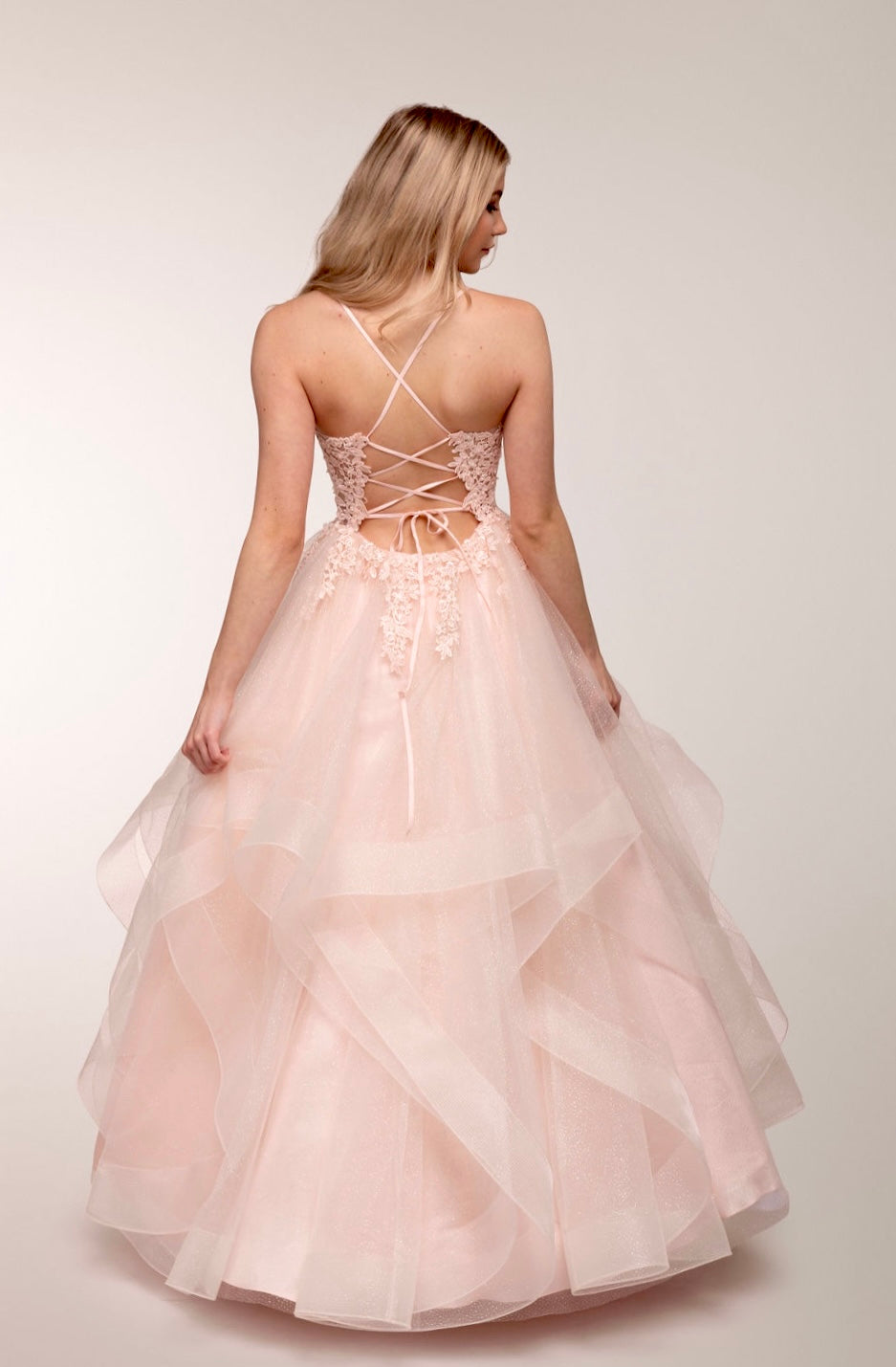 Vaaleanpunainen vanhojentanssimekko, röyhelöhelma, kimallus ja pitsikoristeinen yläosa, takaa.