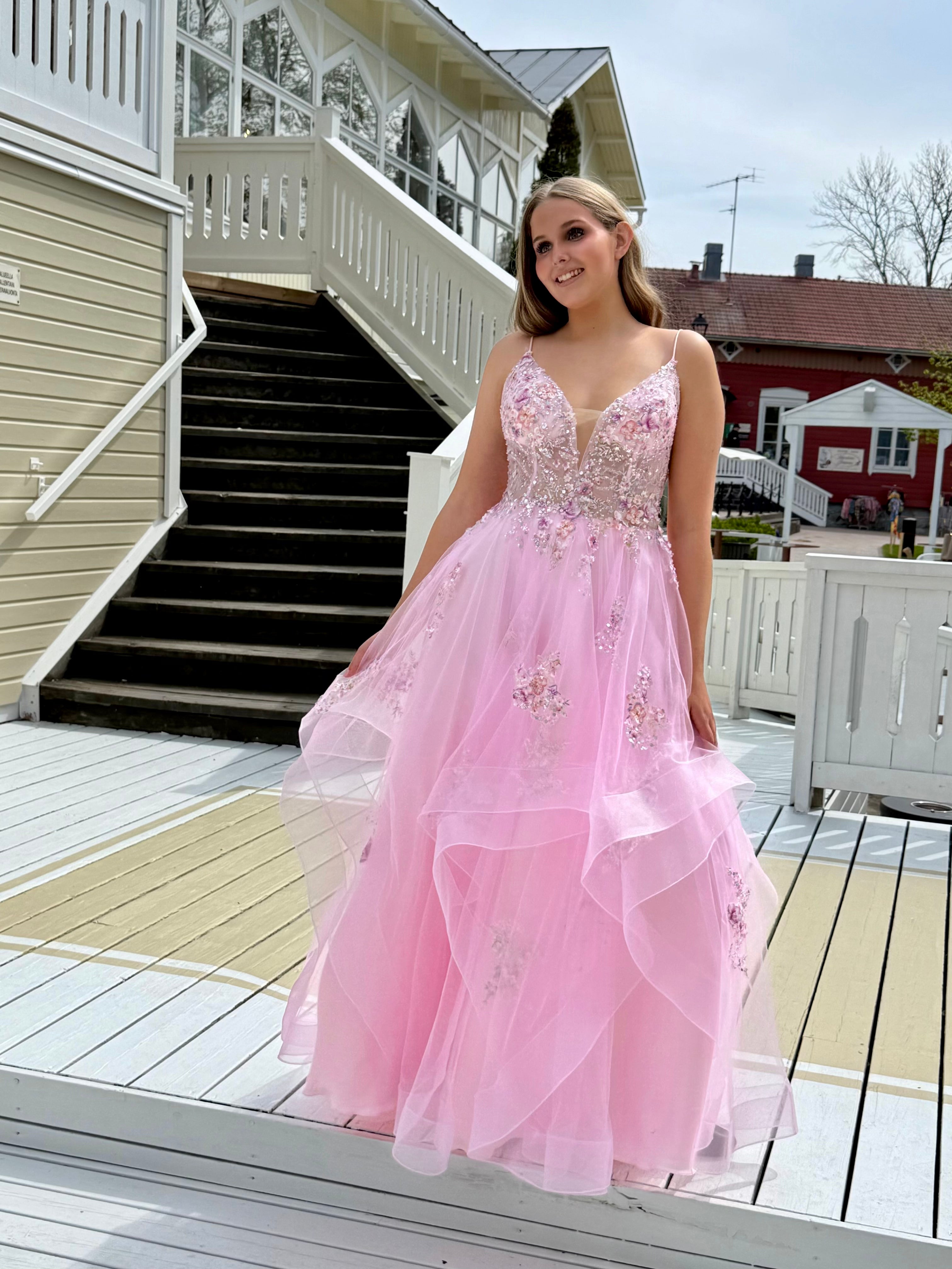 Vaaleanpunainen vanhojentanssimekko kukkapitsillä ja röyhelöhelmalla, edestä.