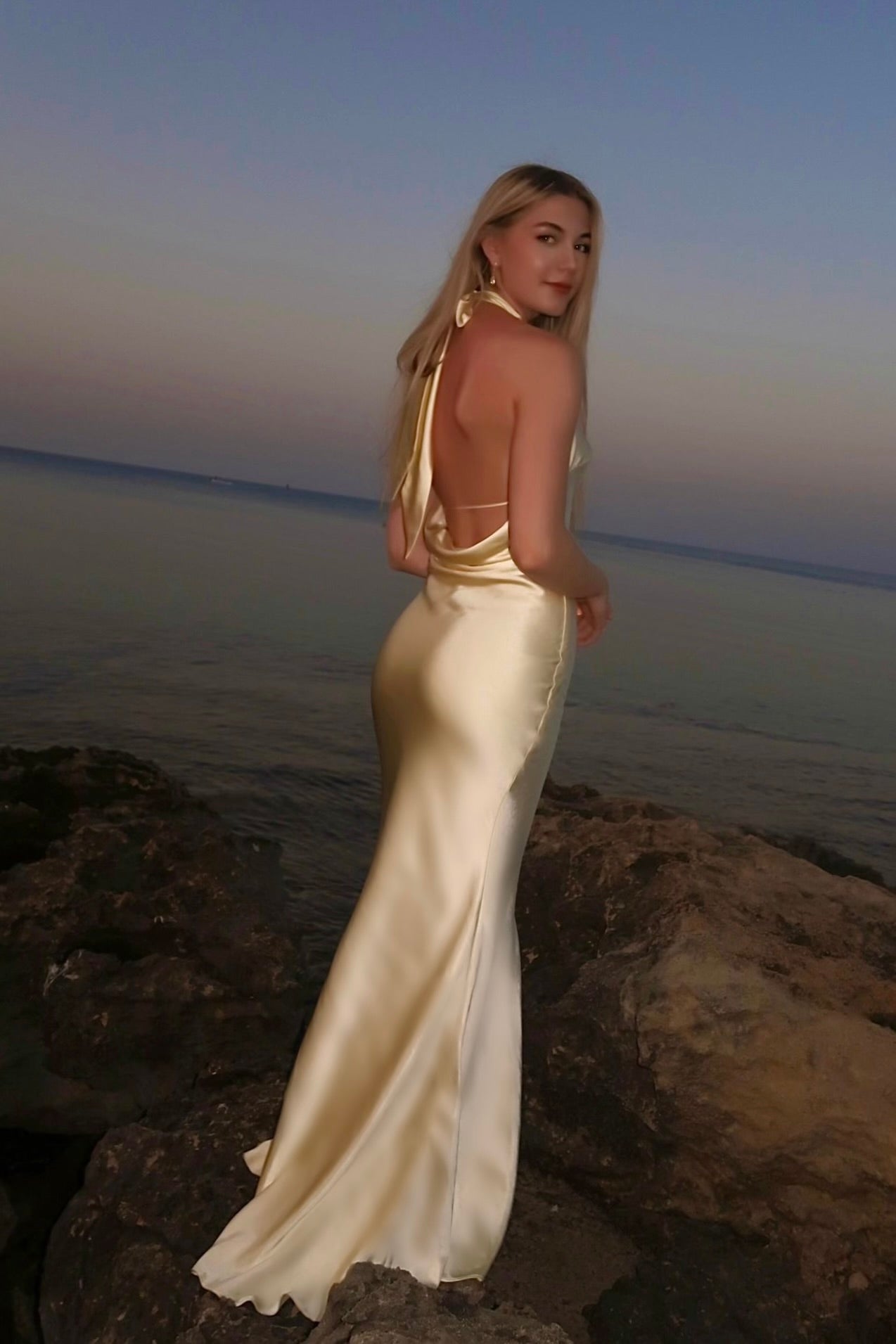 Keltainen halter neck -iltapuku avoimella selällä, takaa.