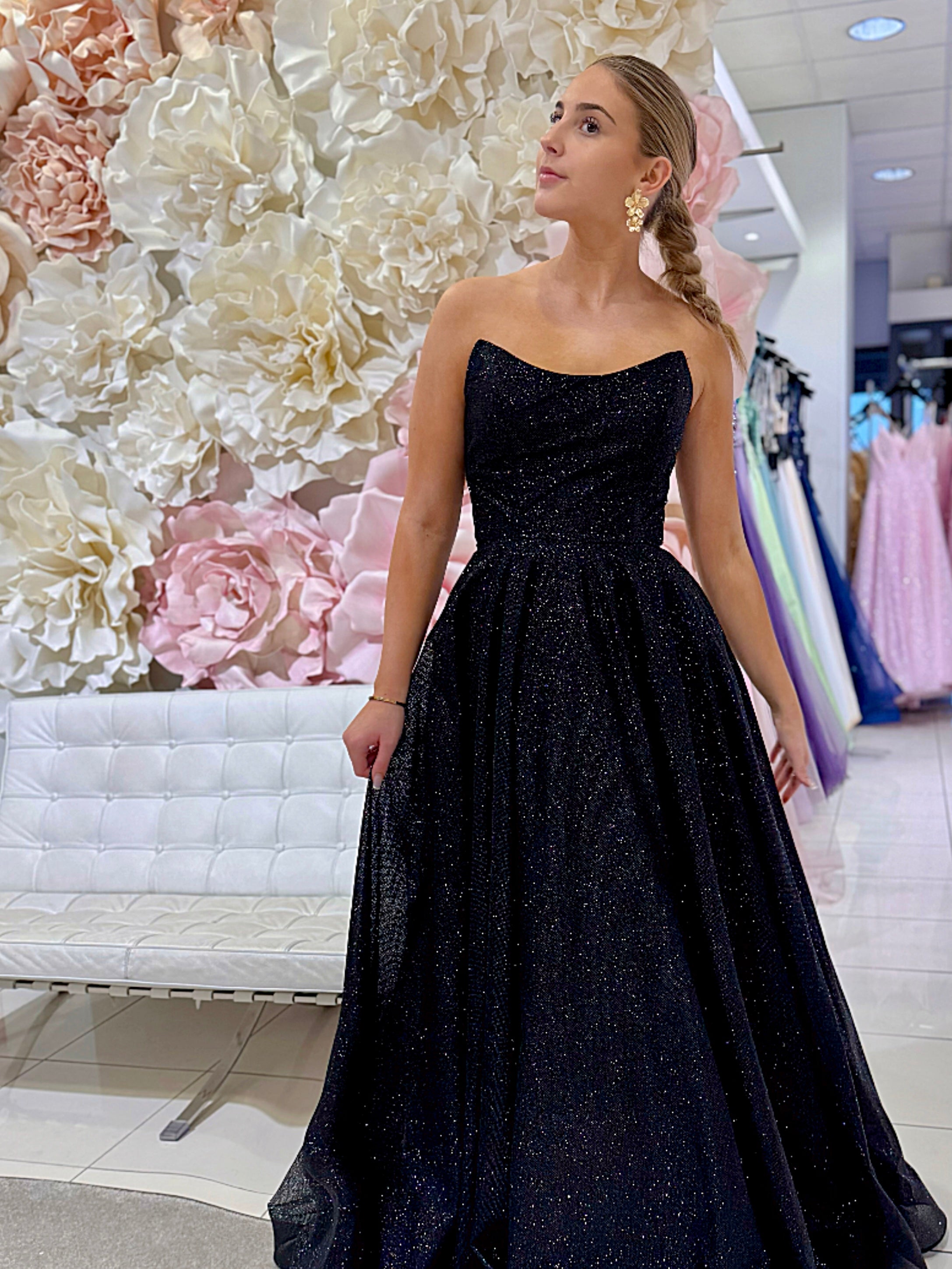 Musta olkaimeton vanhojentanssimekko kimaltavalla kankaalla.