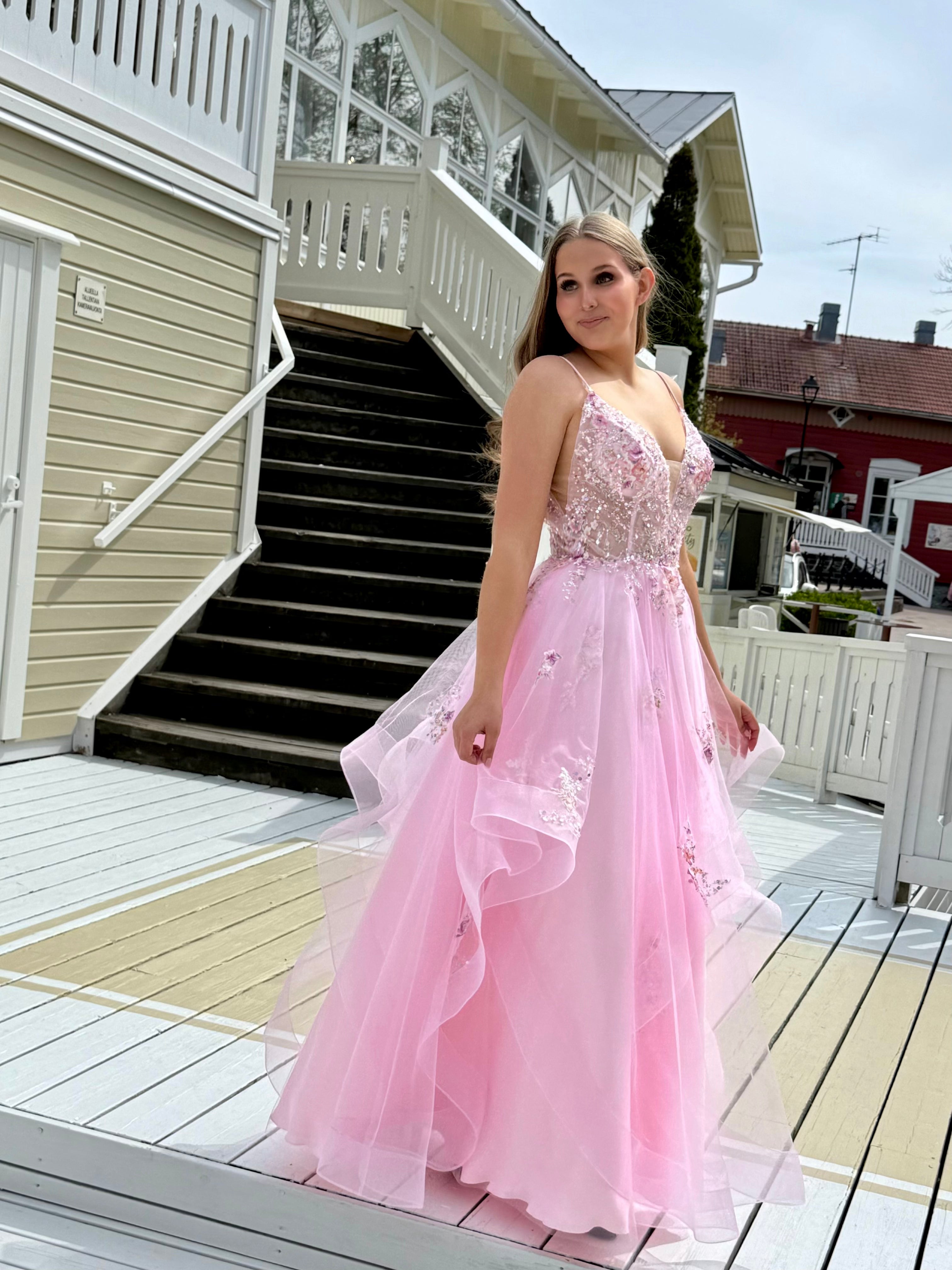 Vaaleanpunainen vanhojentanssimekko kukkapitsillä ja röyhelöhelmalla, sivusta.