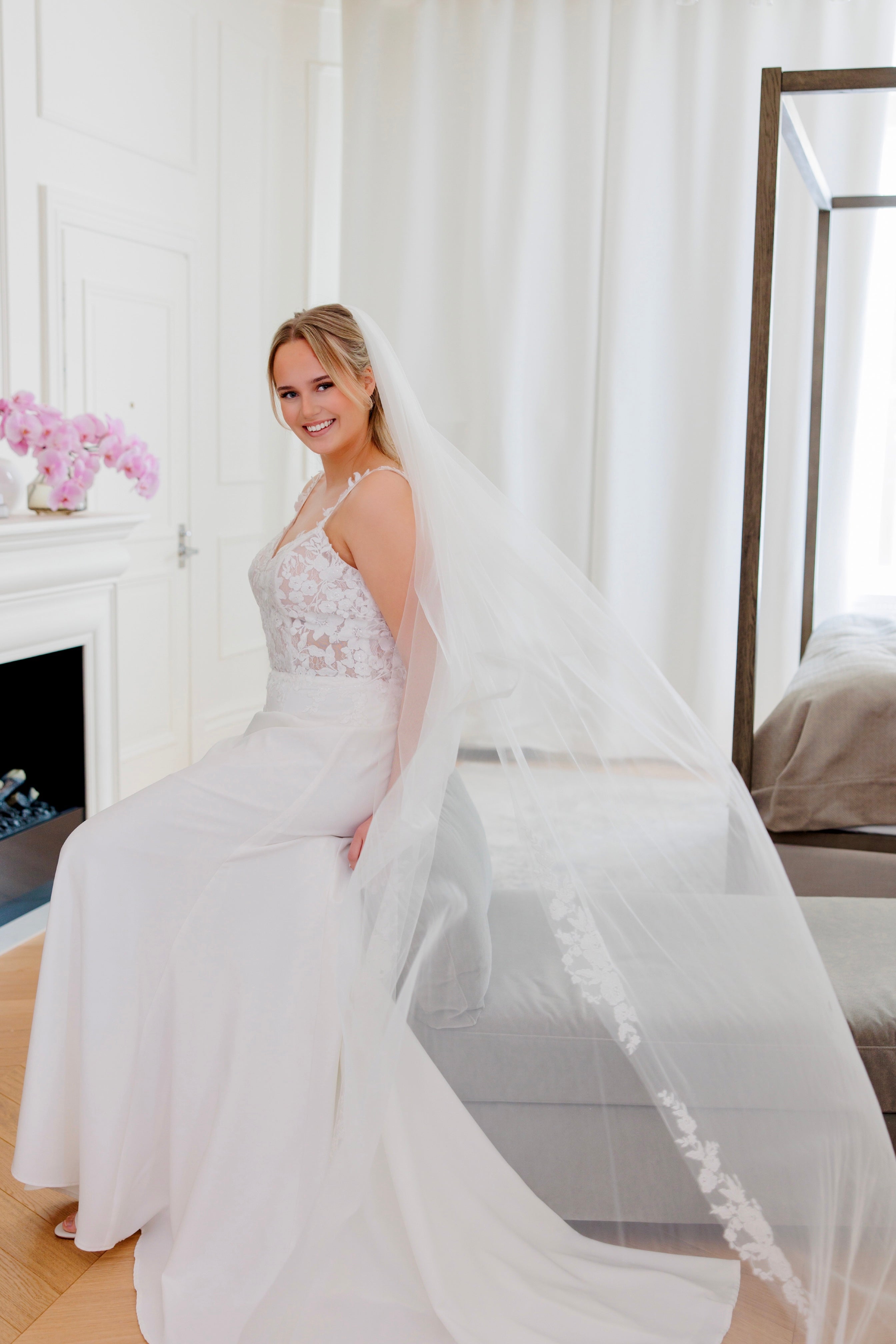 Tyköistuva häämekko ohutolkaisilla, pitsiyksityiskohdilla ja näyttävällä laahuksella.