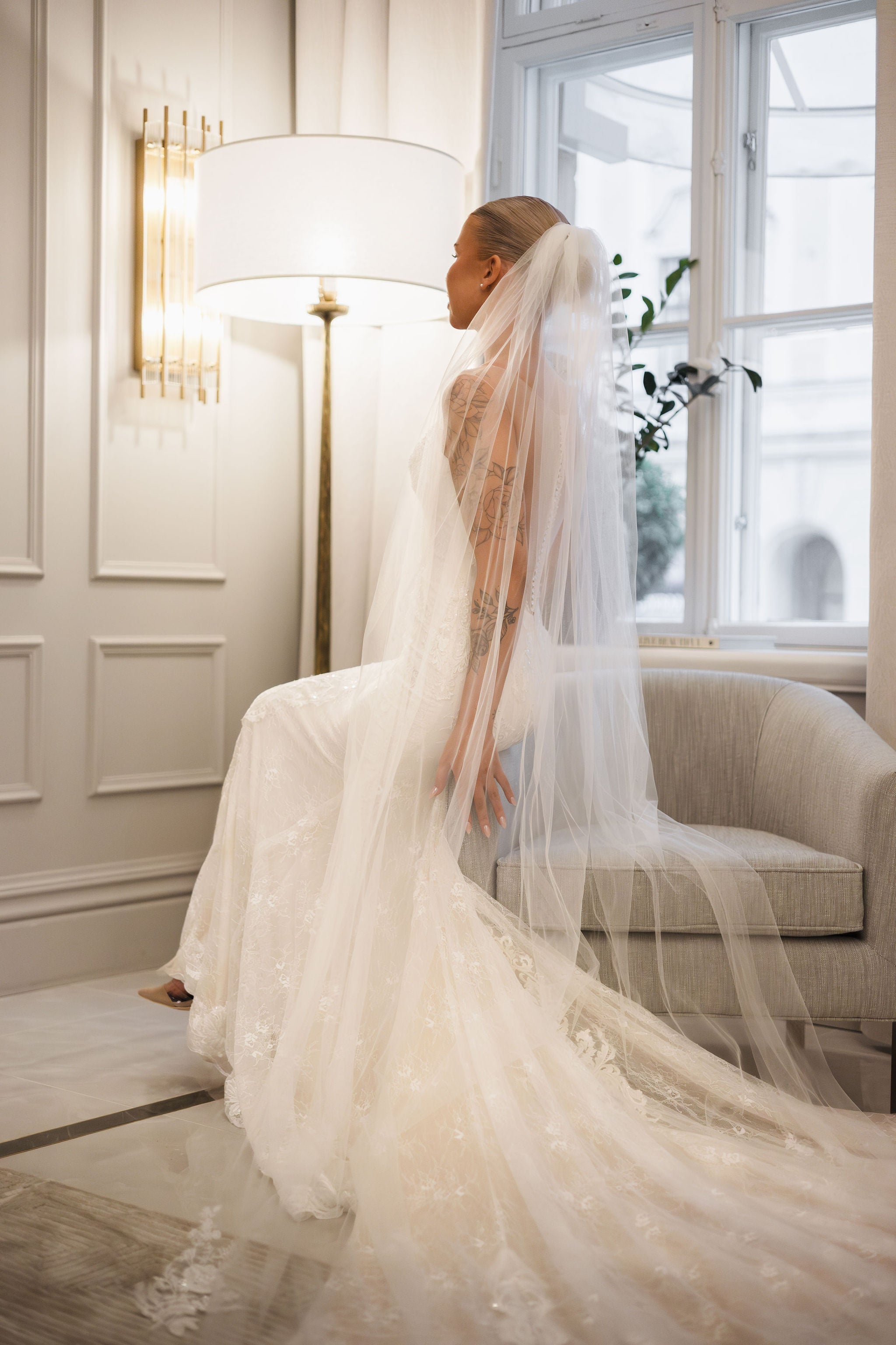 Tyköistuva häämekko pitsiyksityiskohdilla ja näyttävällä laahuksella.