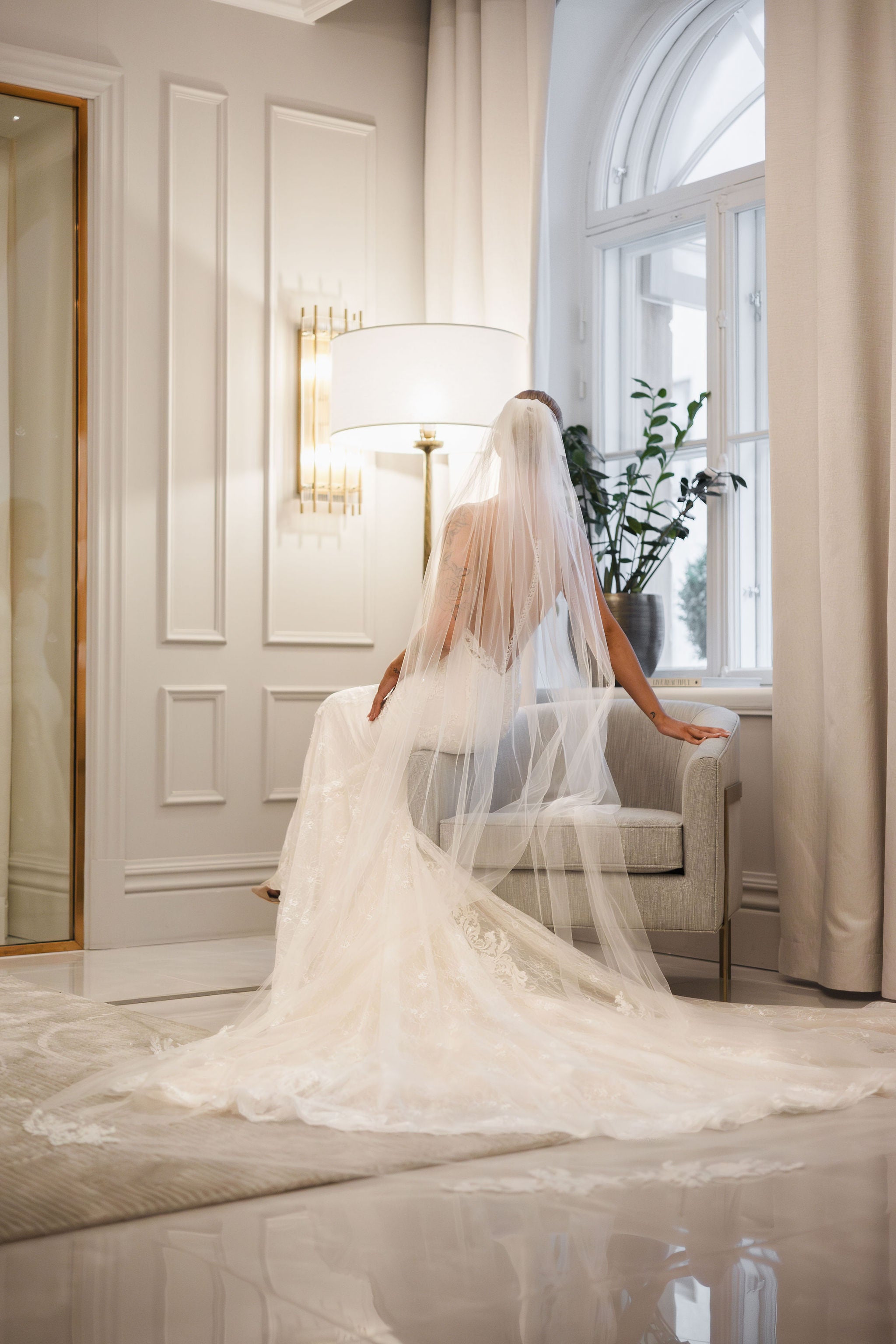 Tyköistuva häämekko pitsiyksityiskohdilla ja näyttävällä laahuksella.