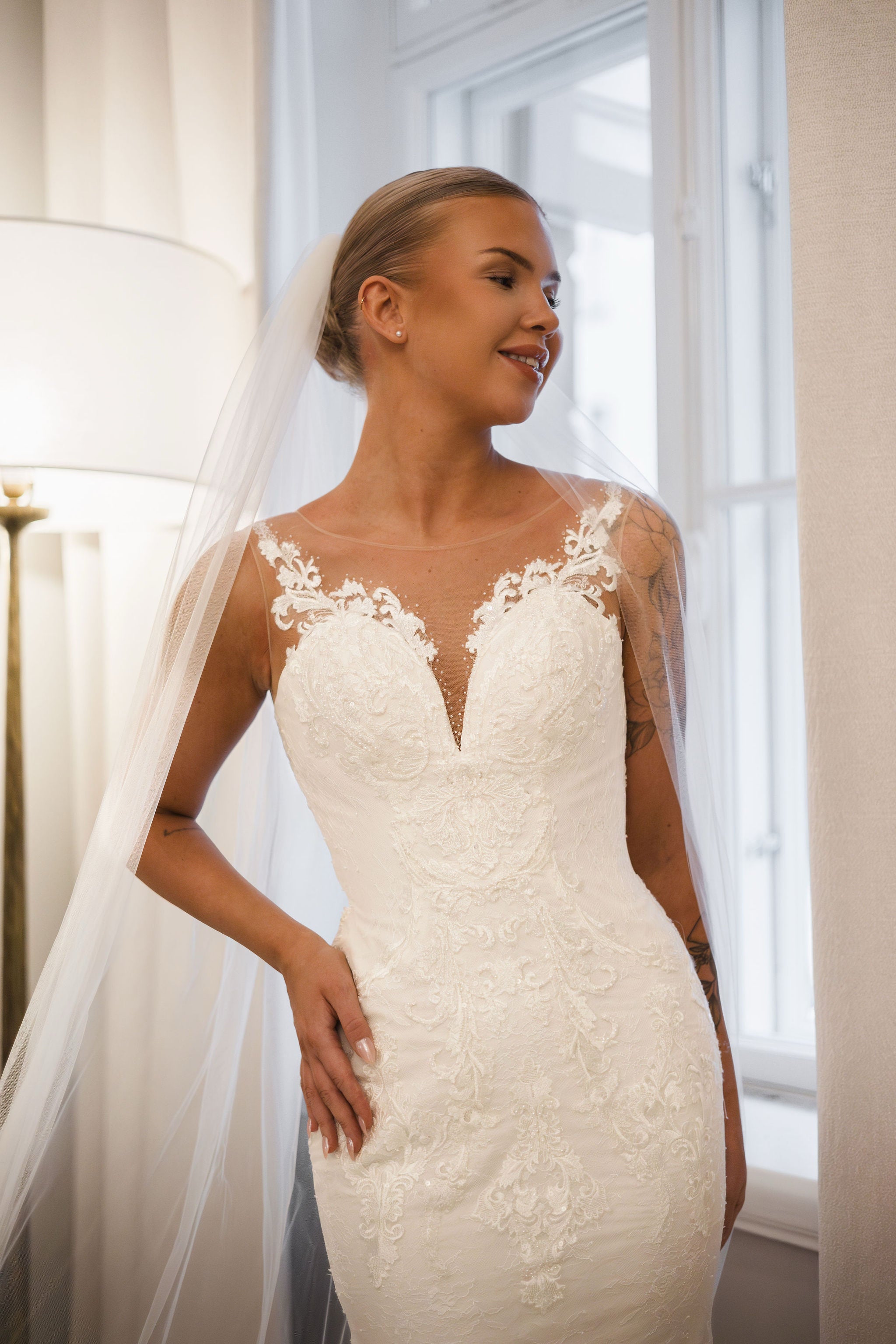 Tyköistuva häämekko pitsiyksityiskohdilla ja näyttävällä laahuksella.