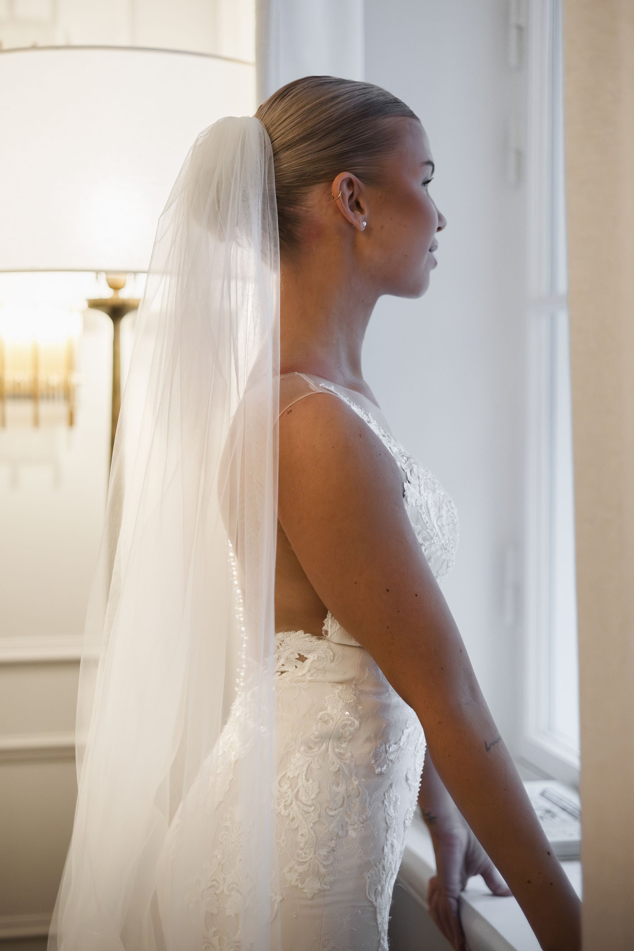 Tyköistuva häämekko pitsiyksityiskohdilla ja näyttävällä laahuksella.