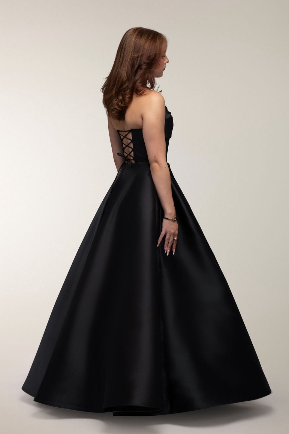 Musta olkaimeton satiininen vanhojentanssimekko, sivusta.