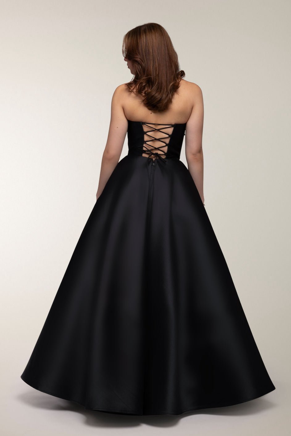 Musta olkaimeton satiininen vanhojentanssimekko, takaa.