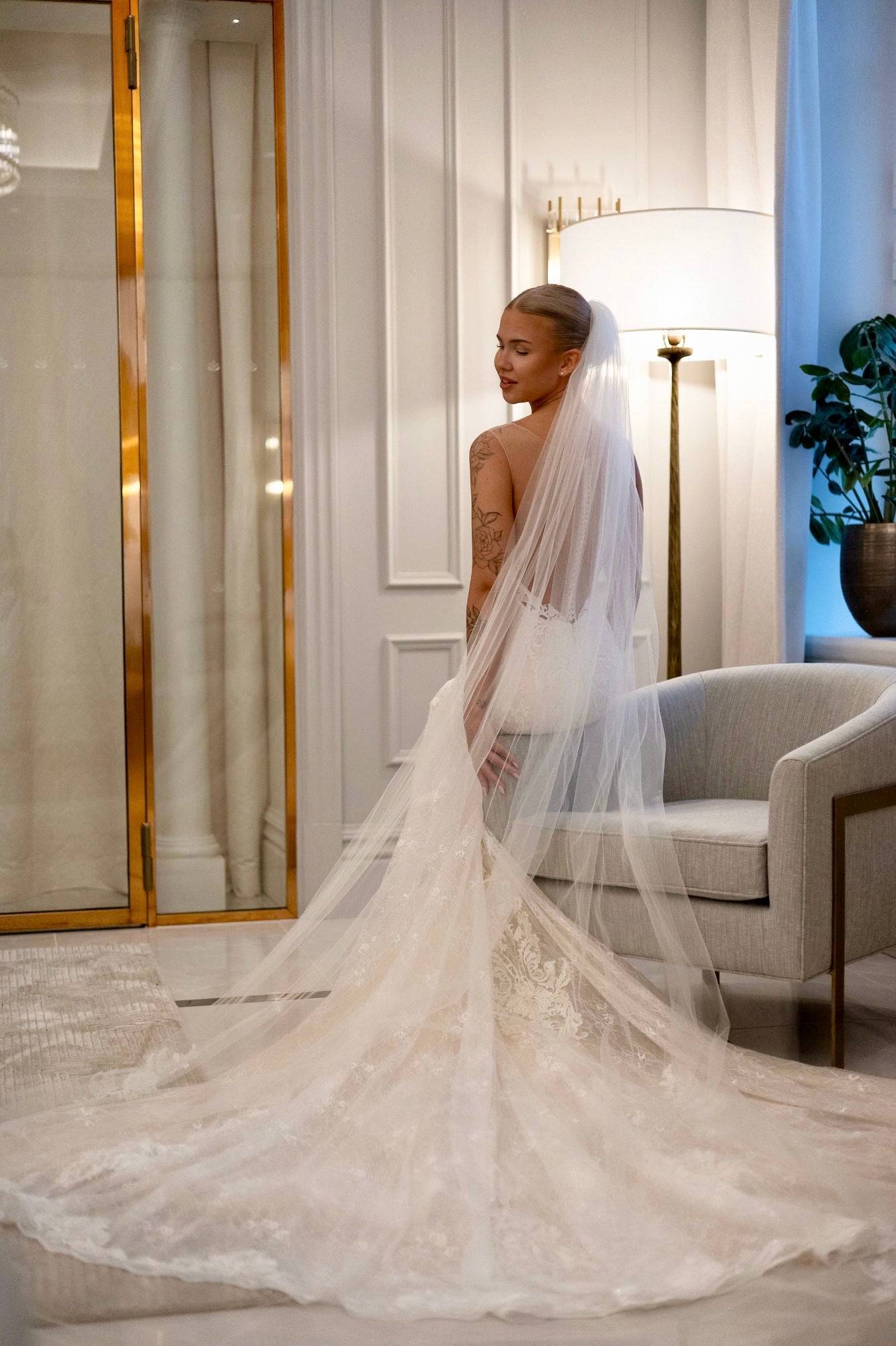 Tyköistuva häämekko pitsiyksityiskohdilla ja näyttävällä laahuksella, takaa.