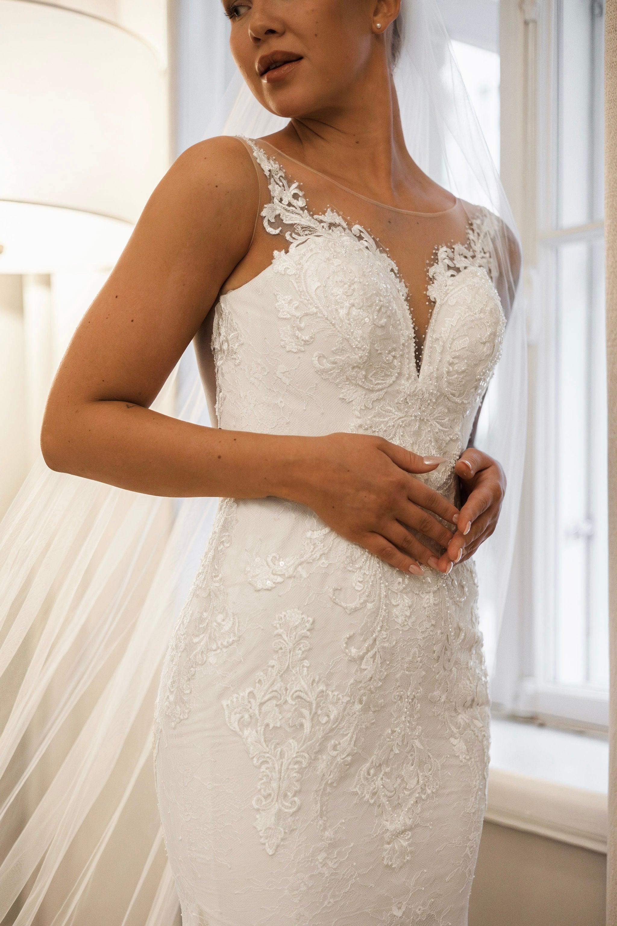 Tyköistuva häämekko pitsiyksityiskohdilla ja näyttävällä laahuksella, läheltä.