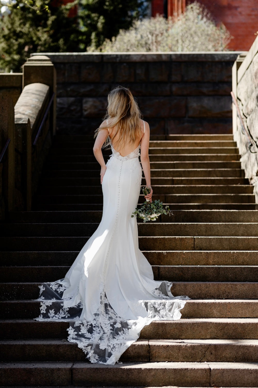 Häämekko ohutolkaimisella yläosalla, kukkabrodeerauksilla ja pitkällä laahuksella. takakuva.