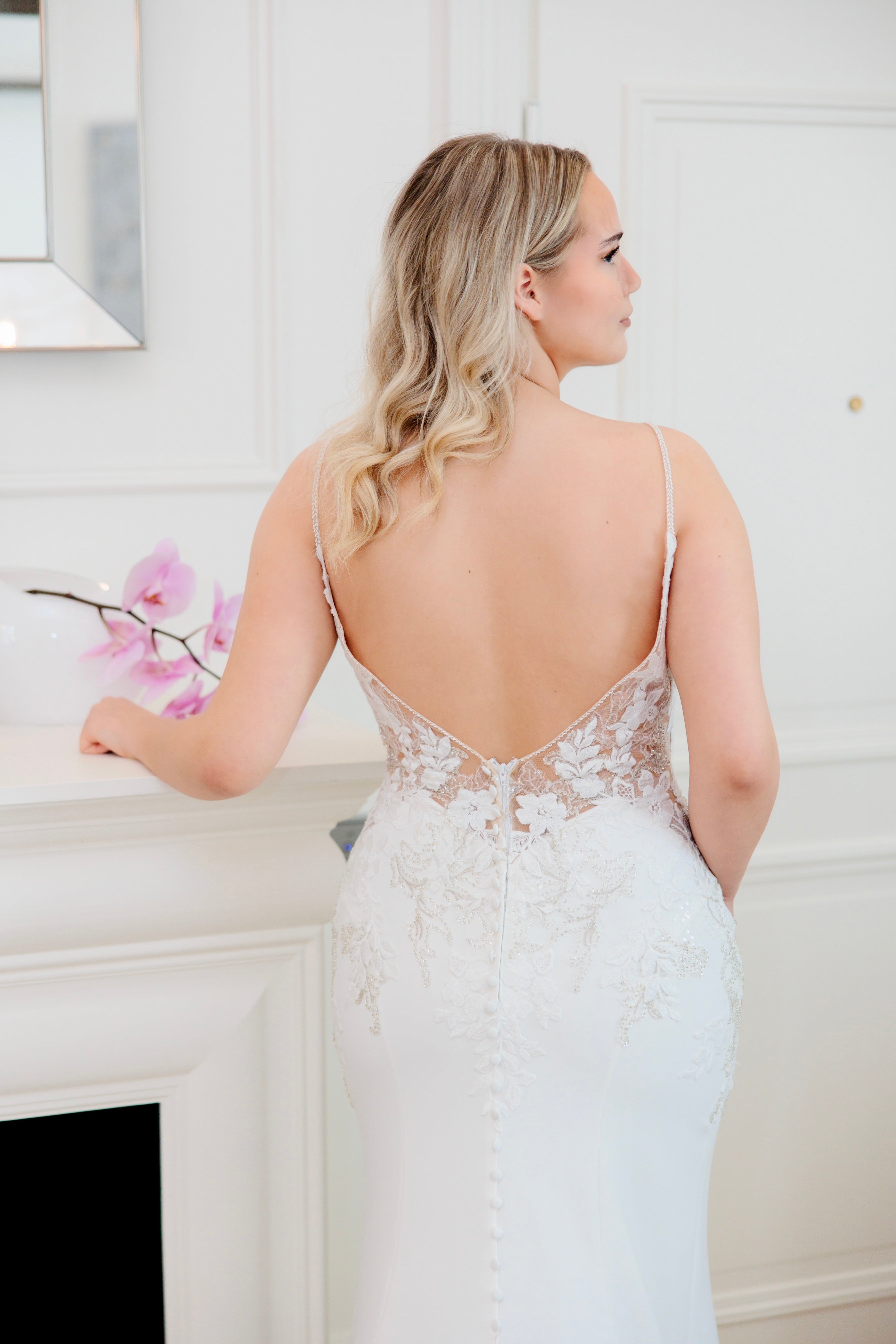 Tyköistuva häämekko ohutolkaisilla, pitsiyksityiskohdilla ja näyttävällä laahuksella, takaa.