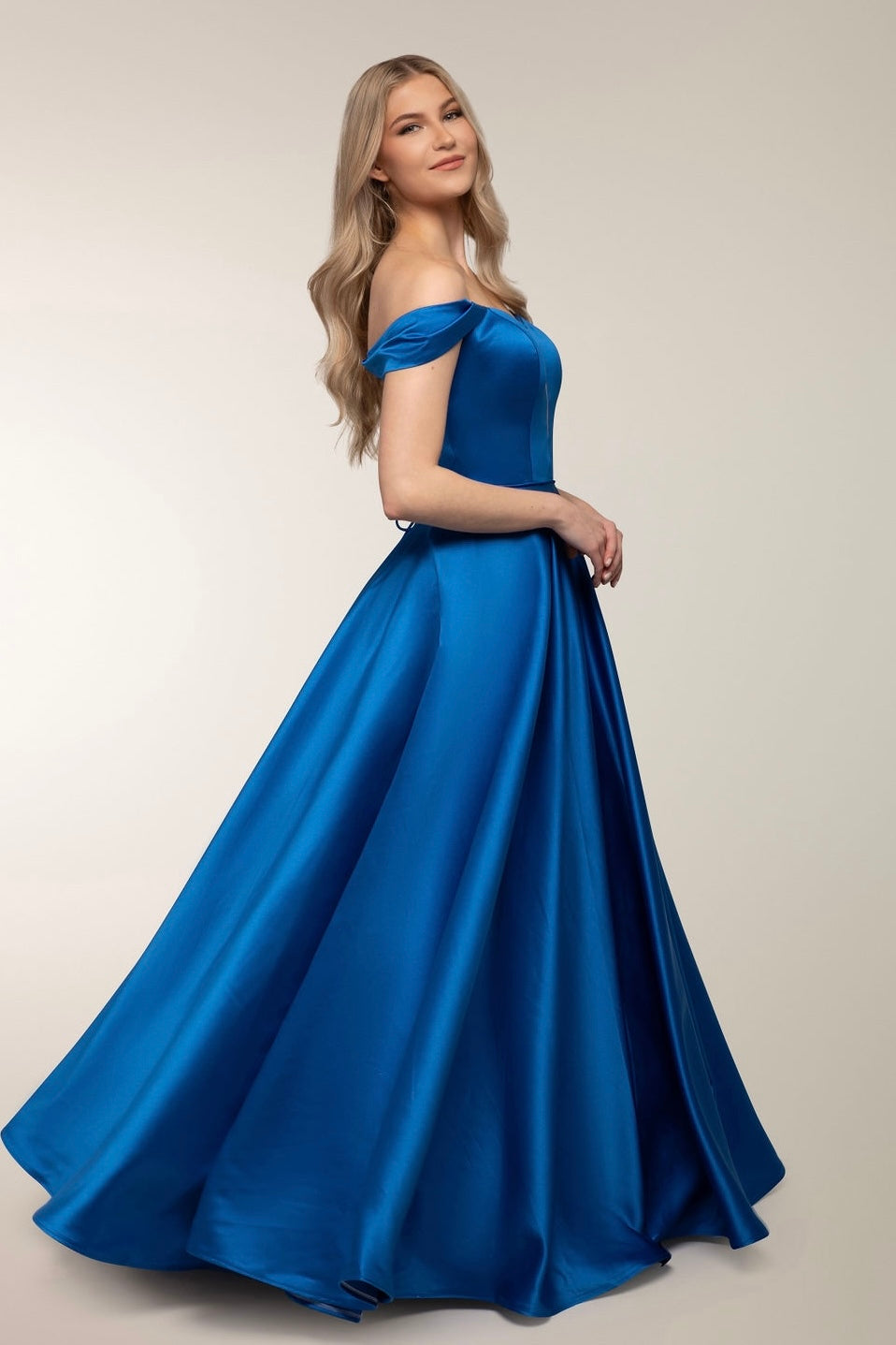 Kirkkaan sininen satiininen vanhojentanssimekko off-shoulder-mallilla, sivusta.