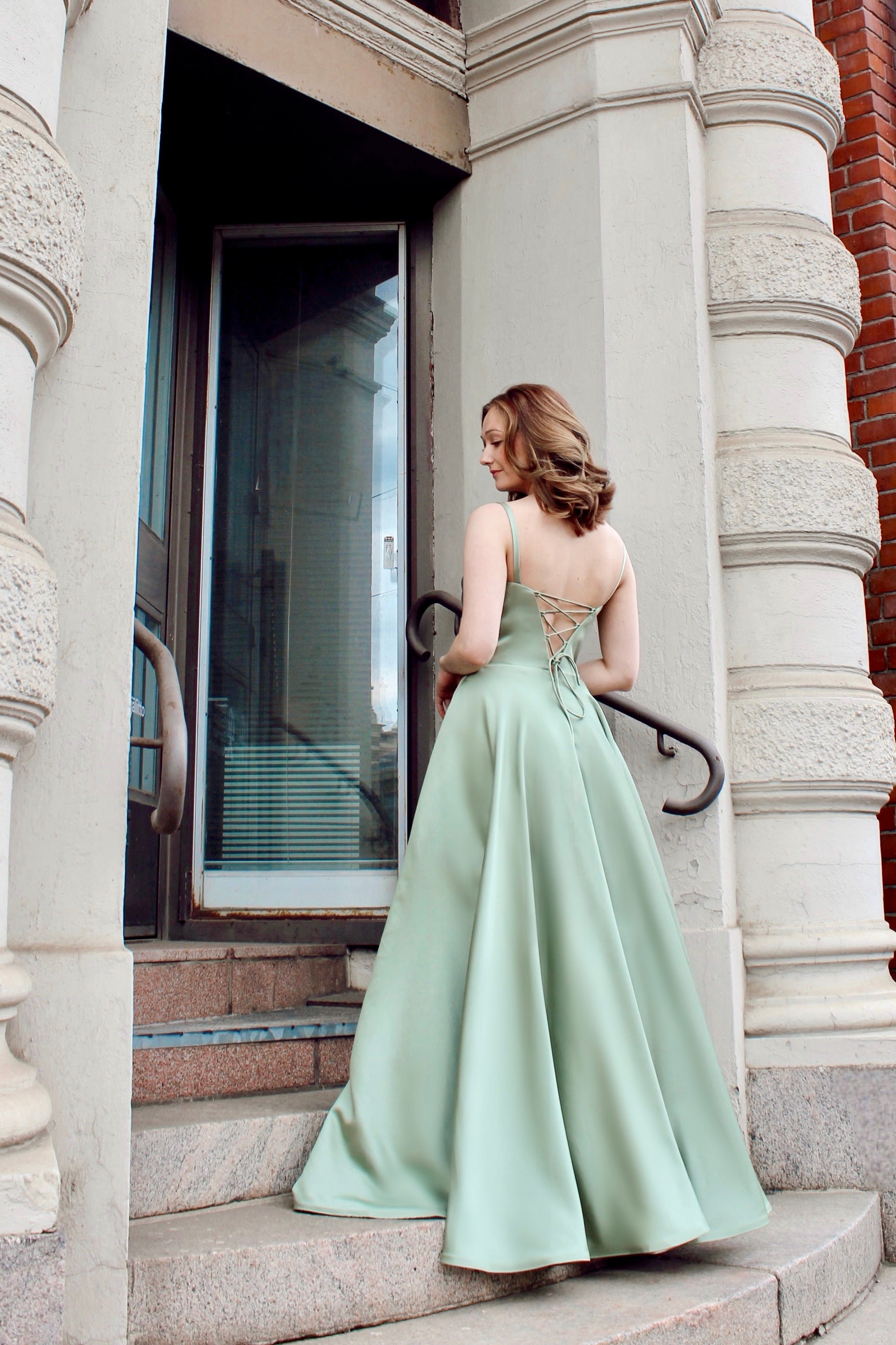 Oliivin sävyinen satiininen vanhojentanssimekko nyörityksellä.