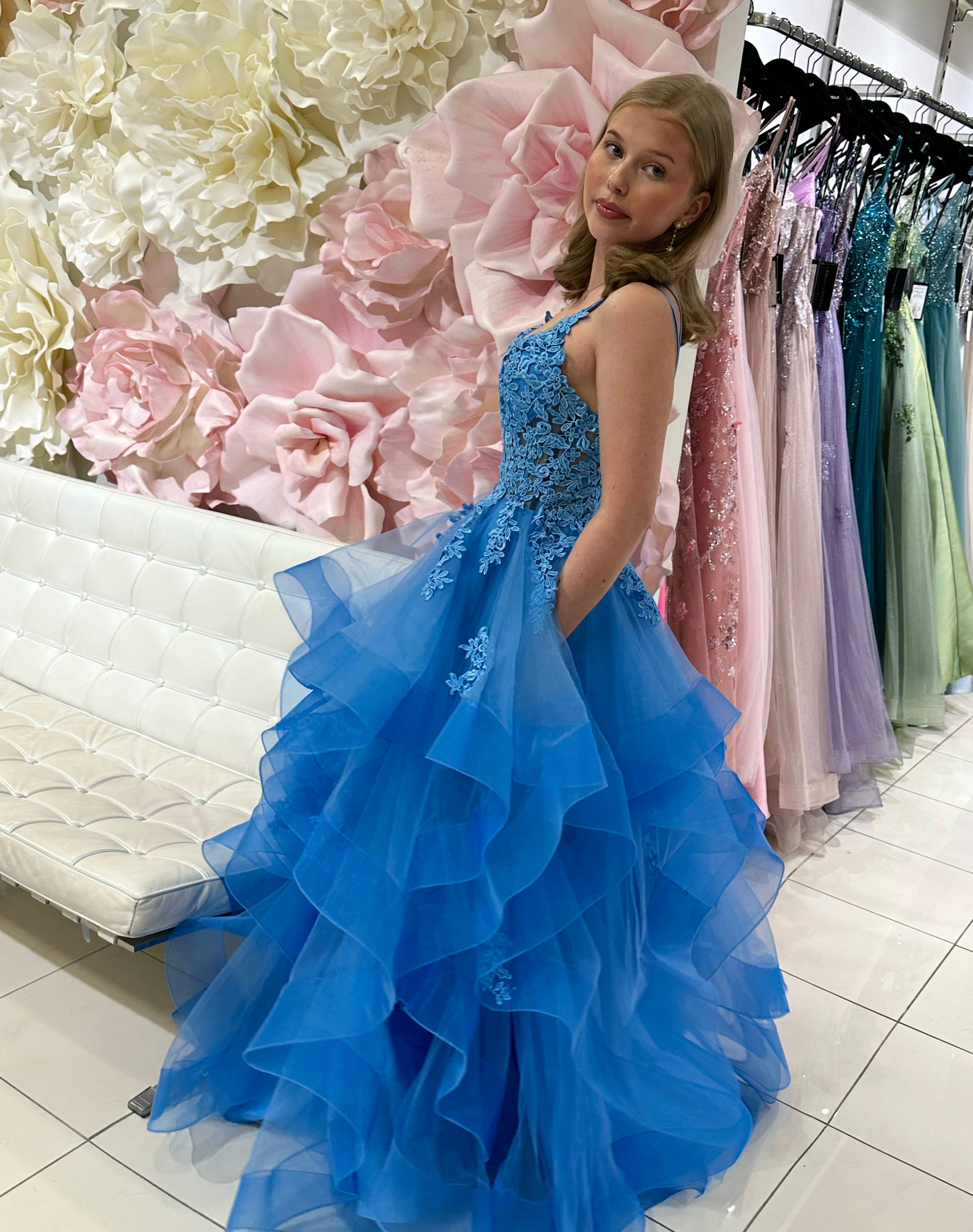 Sininen vanhojentanssimekko, röyhelöhelma ja pitsikoristeltu yläosa.