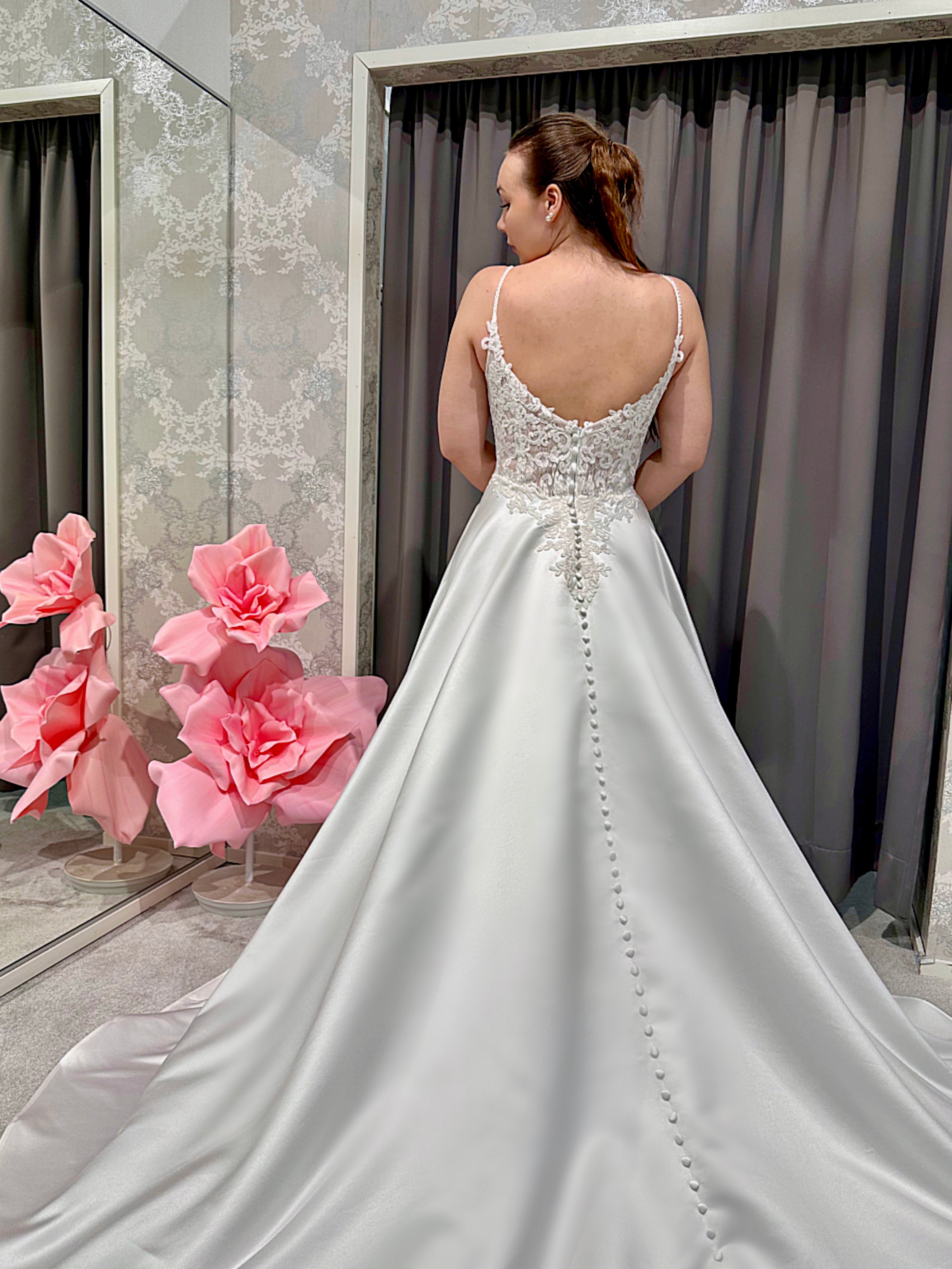 Häämekko, jossa kirjailtu pitsiyläosa, sirot olkaimet ja linjakas satiinihelma, takaa.