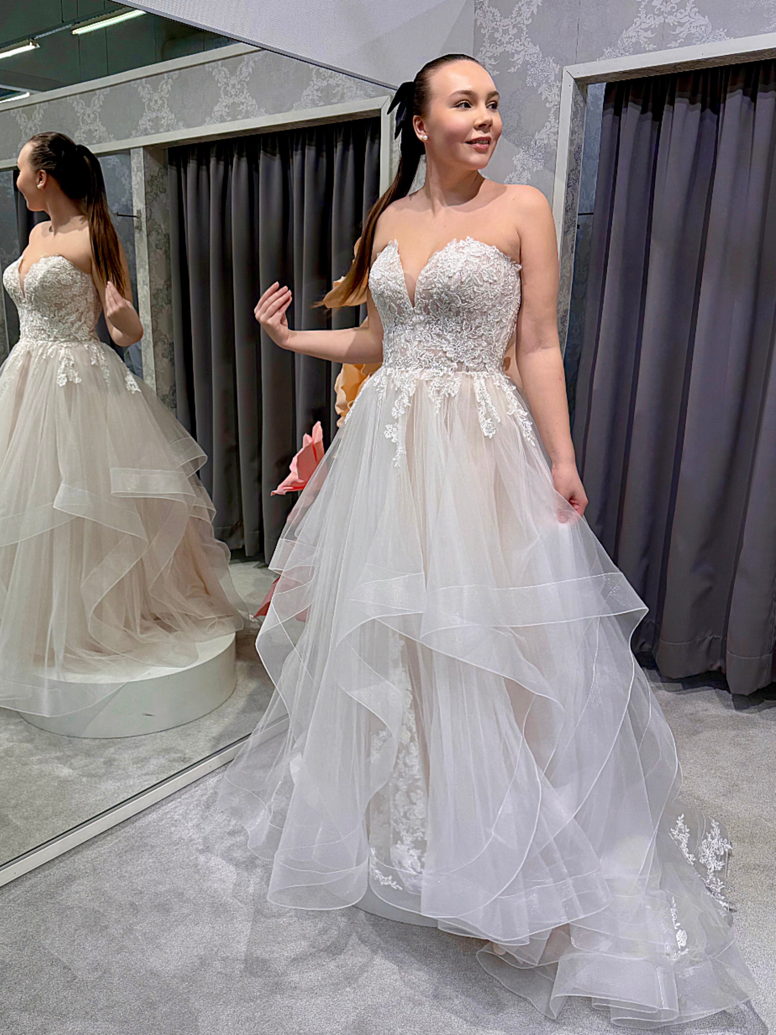 Häämekko, jossa kaunis pitsiyläosa ja röyhelöhelma, romanttinen ja elegantti, edestä.