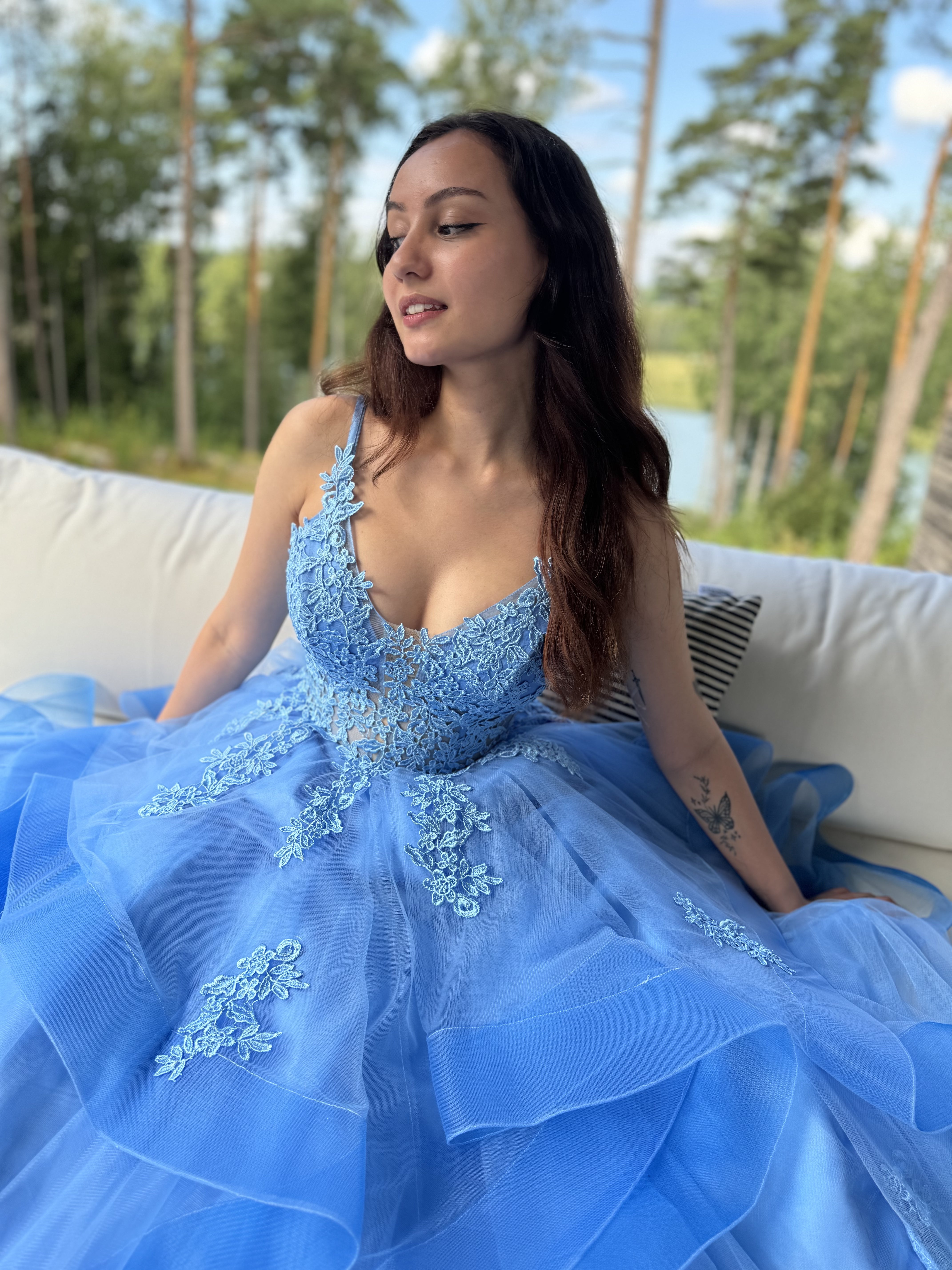 Sininen vanhojentanssimekko, röyhelöhelma ja pitsikoristeltu yläosa.