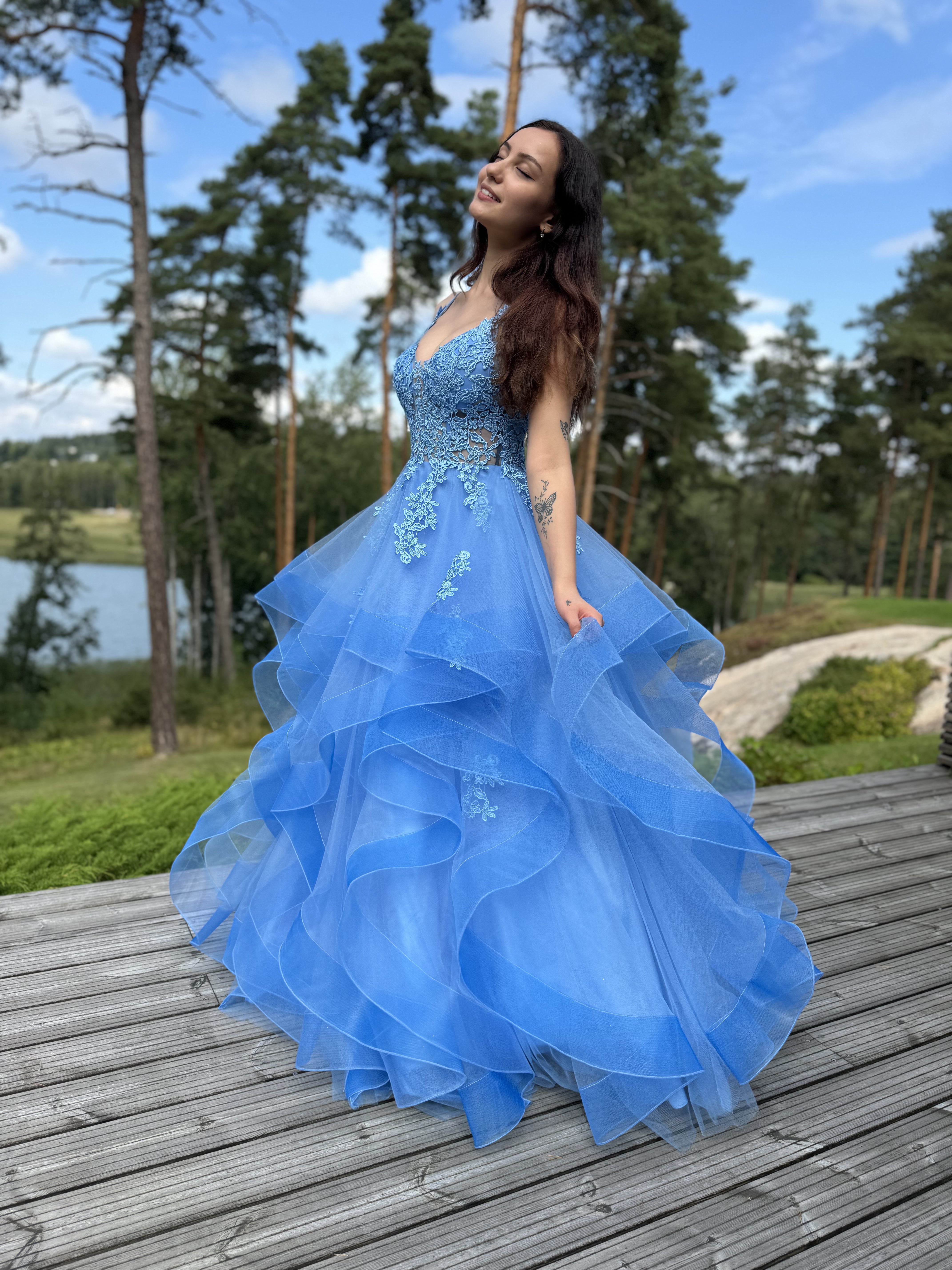 Sininen vanhojentanssimekko, röyhelöhelma ja pitsikoristeltu yläosa.