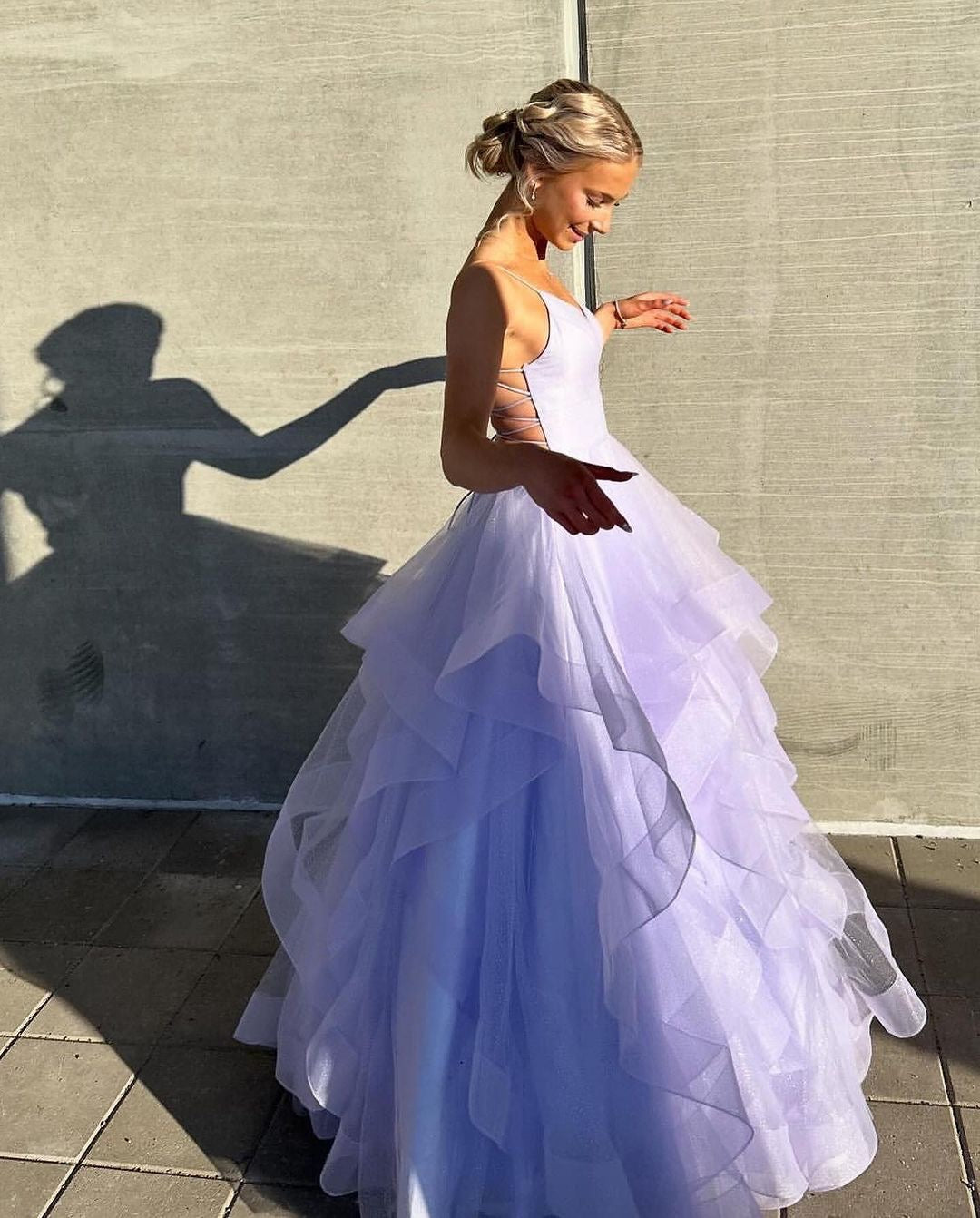 Violetti vanhojentanssimekko kimaltavalla röyhelöhelmalla ja avoimella selällä, sivusta.