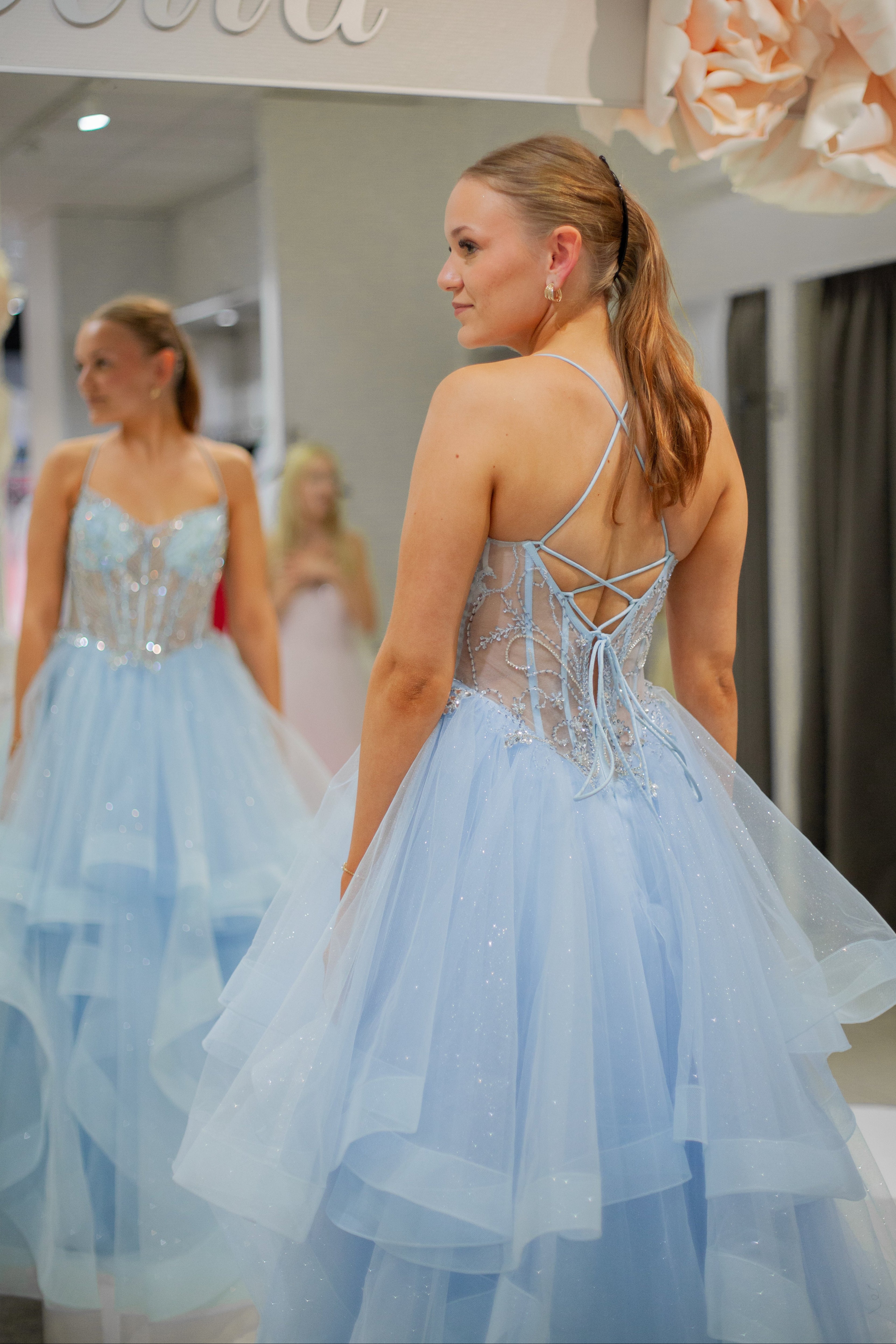 Vaaleansininen kimaltava vanhojentanssimekko röyhelöhelmalla ja kirjailulla yläosalla.