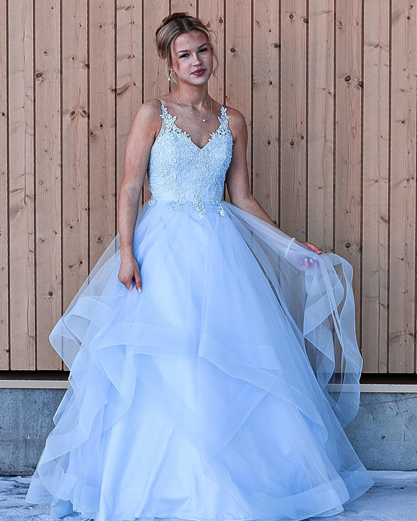 Vaaleansininen vanhojentanssimekko pitsiyläosalla ja röyhelöhelmalla.