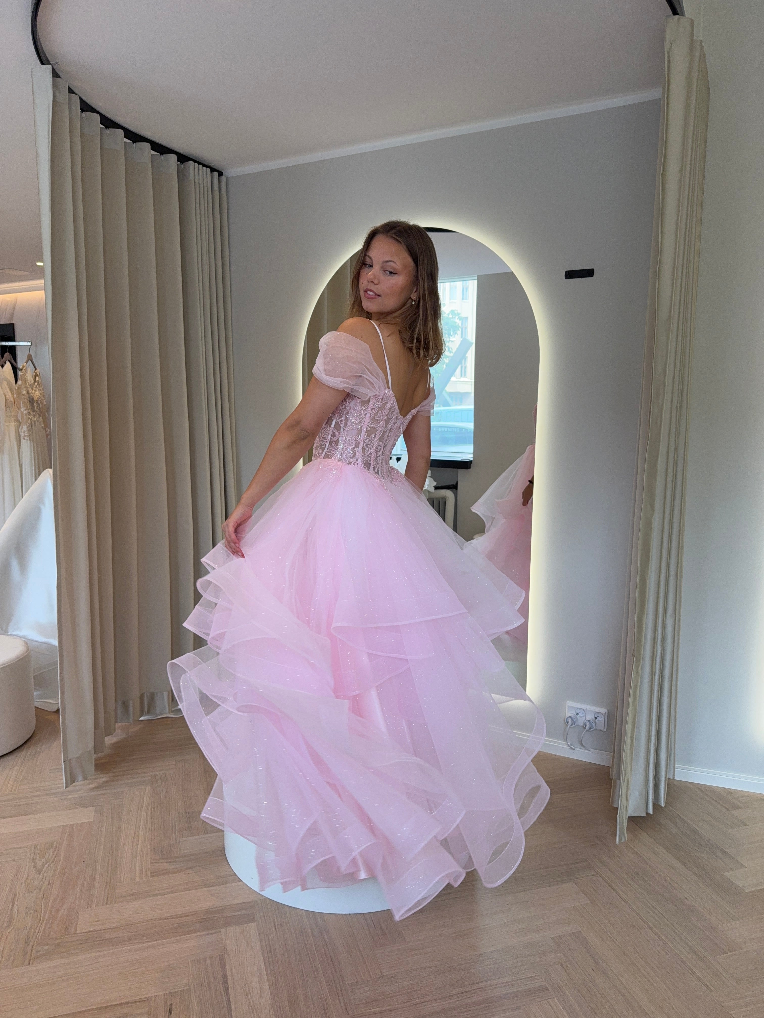 Pinkki kimaltava vanhojentanssimekko off shoulder -mallisella pitsiyläosalla ja röyhelöhelmalla.