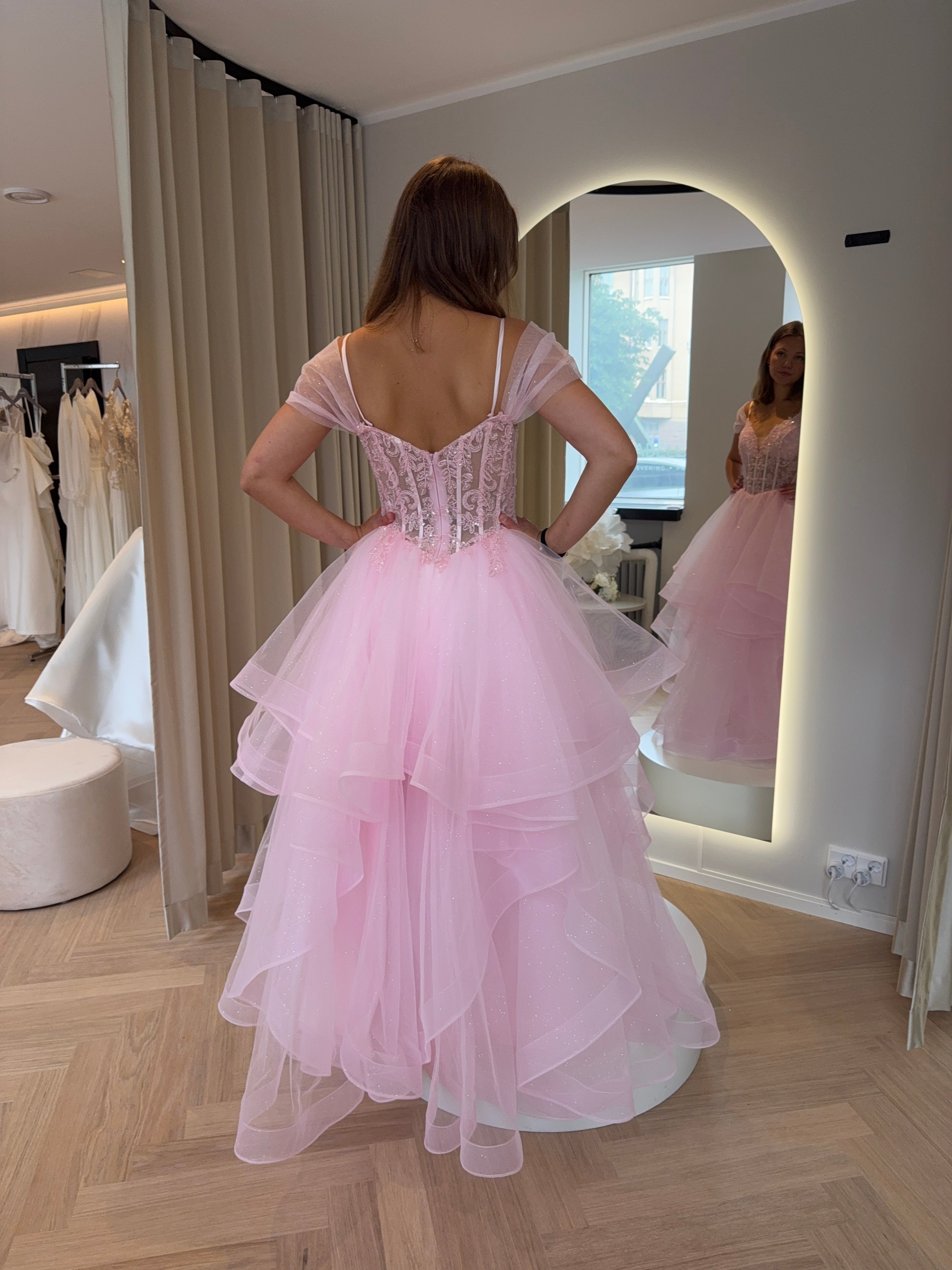 Pinkki kimaltava vanhojentanssimekko off shoulder -mallisella pitsiyläosalla ja röyhelöhelmalla.