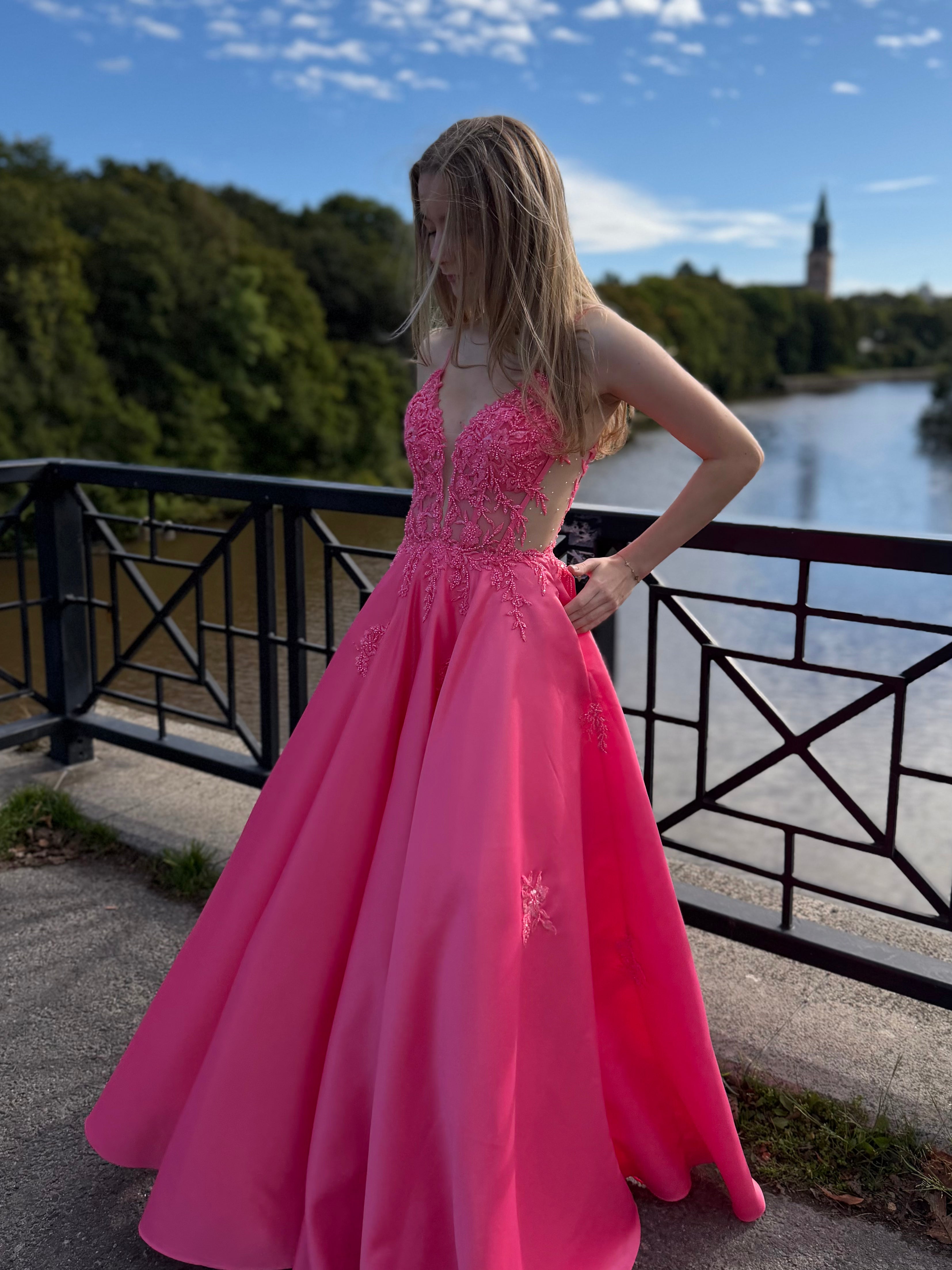 Fuksianpinkki vanhojentanssimekko pitsiyläosalla ja suoralla satiinihelmalla.