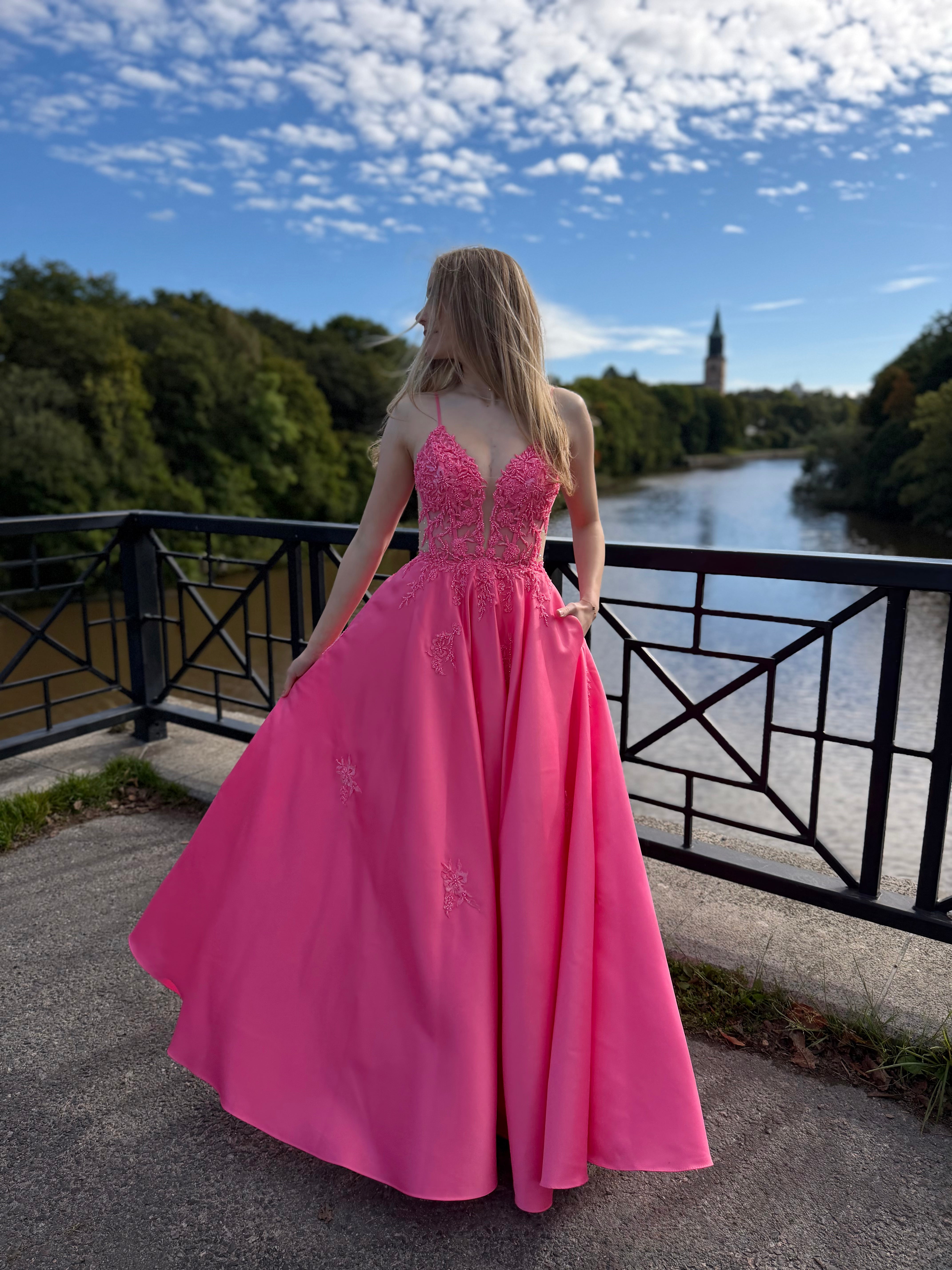 Fuksianpinkki vanhojentanssimekko pitsiyläosalla ja suoralla satiinihelmalla.