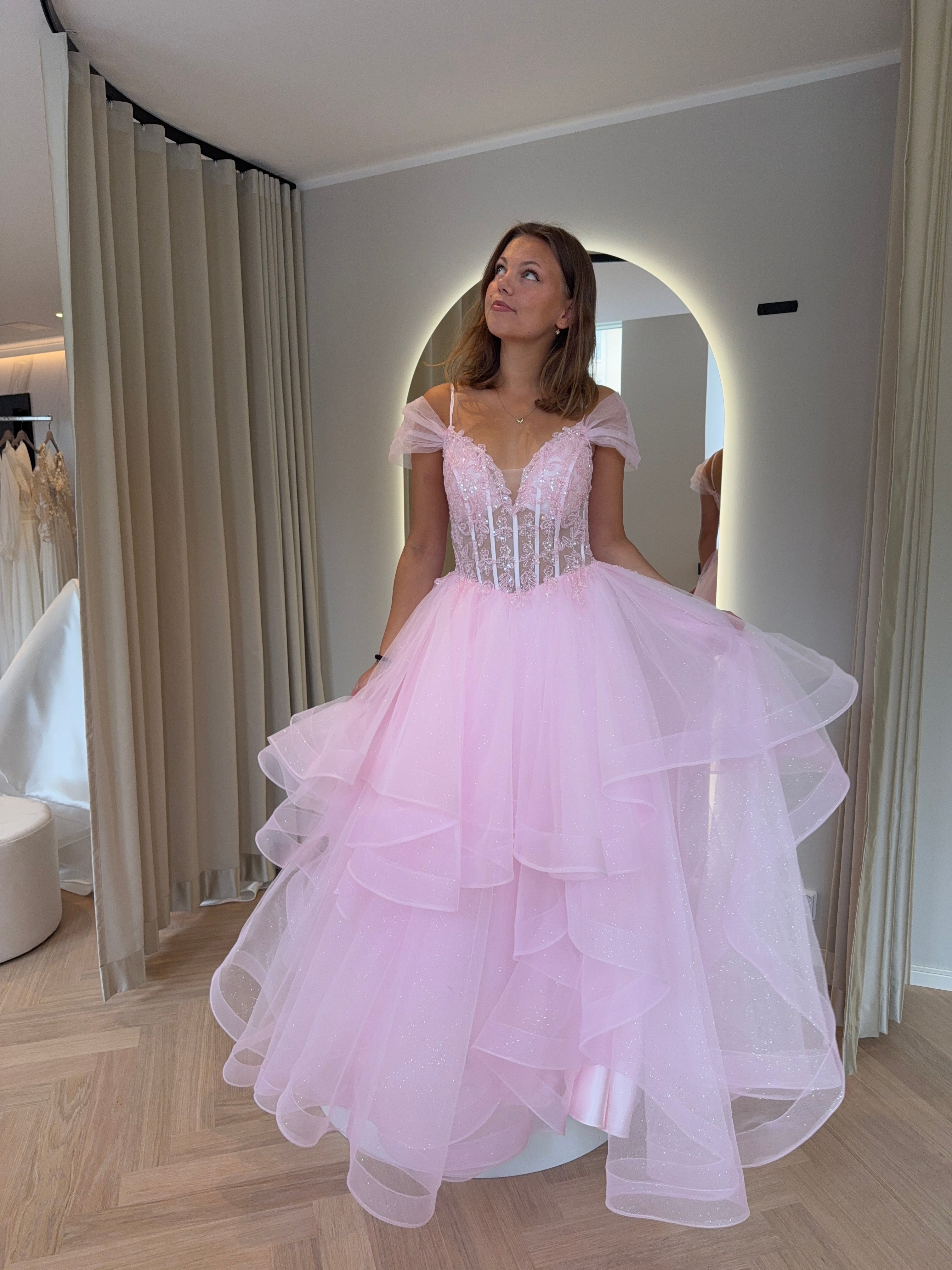 Pinkki kimaltava vanhojentanssimekko off shoulder -mallisella pitsiyläosalla ja röyhelöhelmalla.