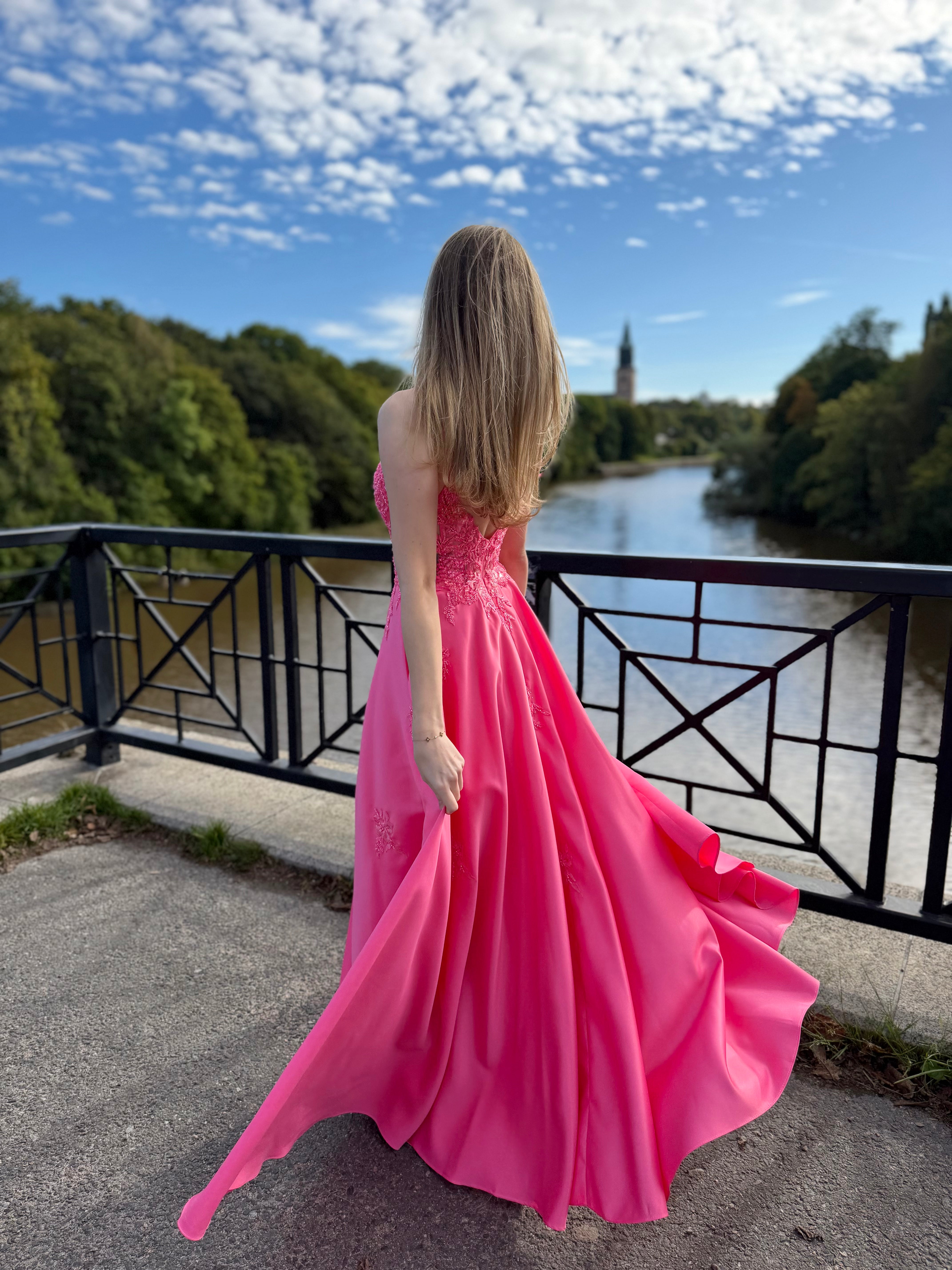 Fuksianpinkki vanhojentanssimekko pitsiyläosalla ja suoralla satiinihelmalla.