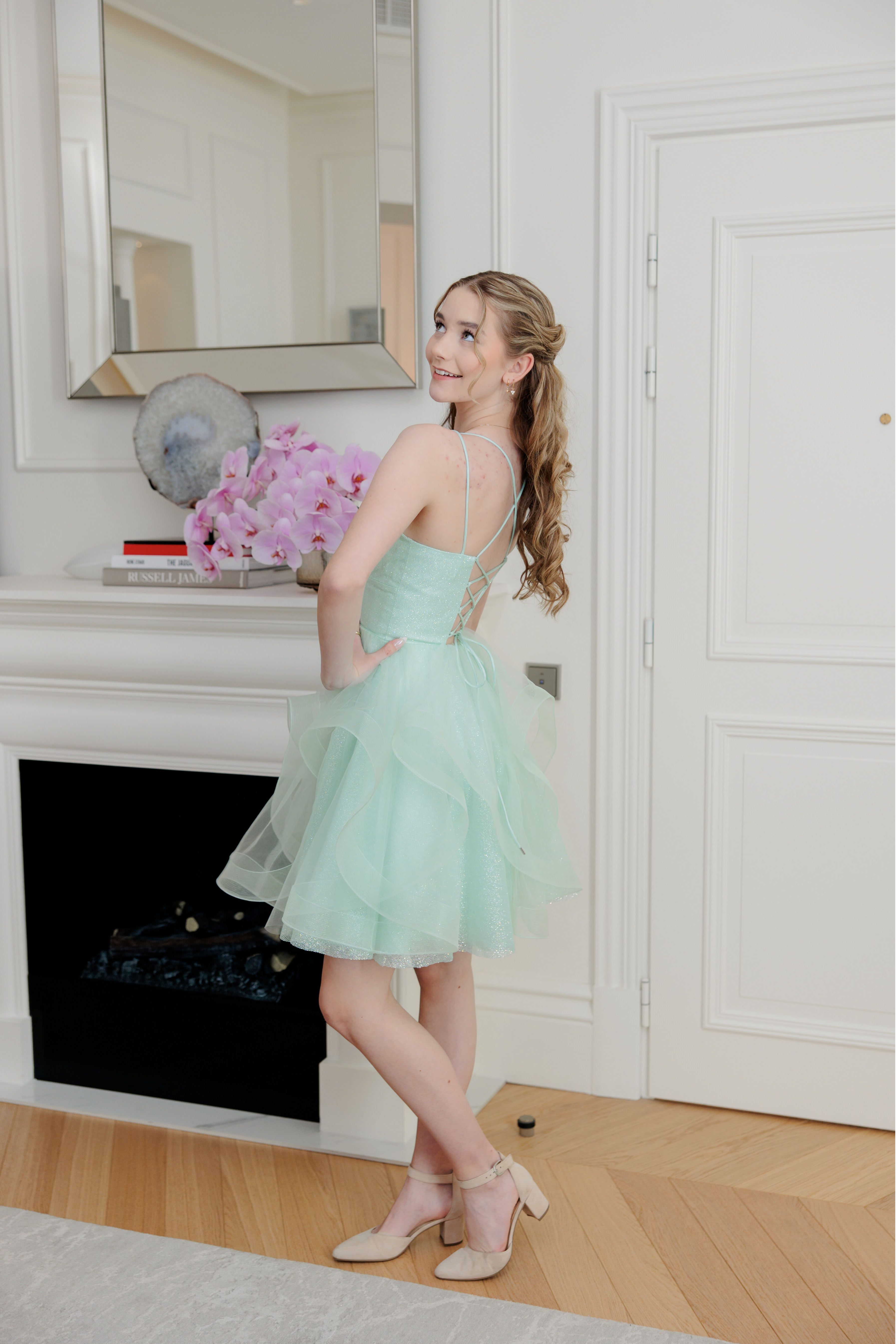 Mintun värinen juhlamekko röyhelöhelmalla ja kimalluksella rippijuhliin, takana.