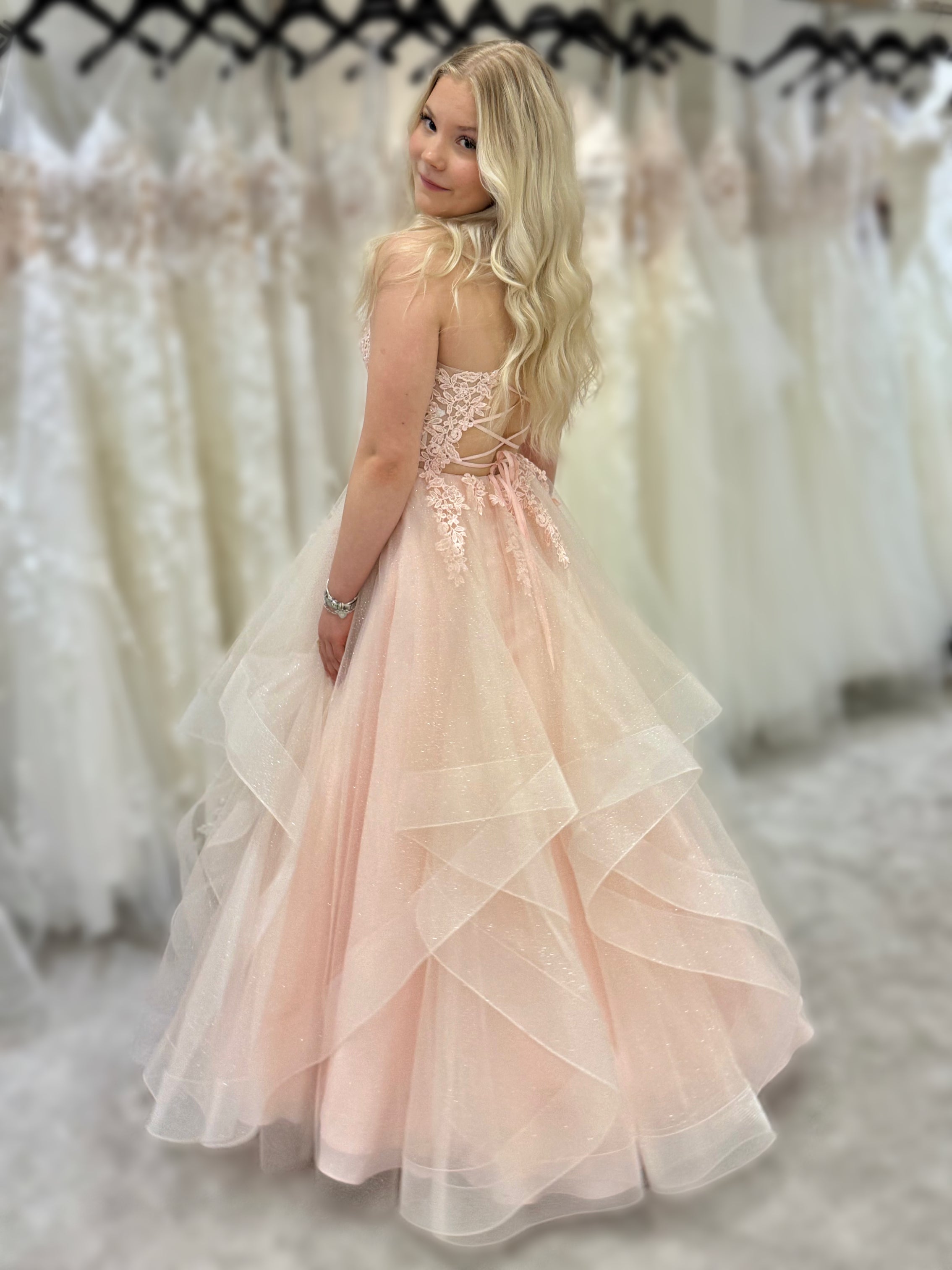 Vaaleanpunainen vanhojentanssimekko, röyhelöhelma, kimallus ja pitsikoristeinen yläosa, takaa.