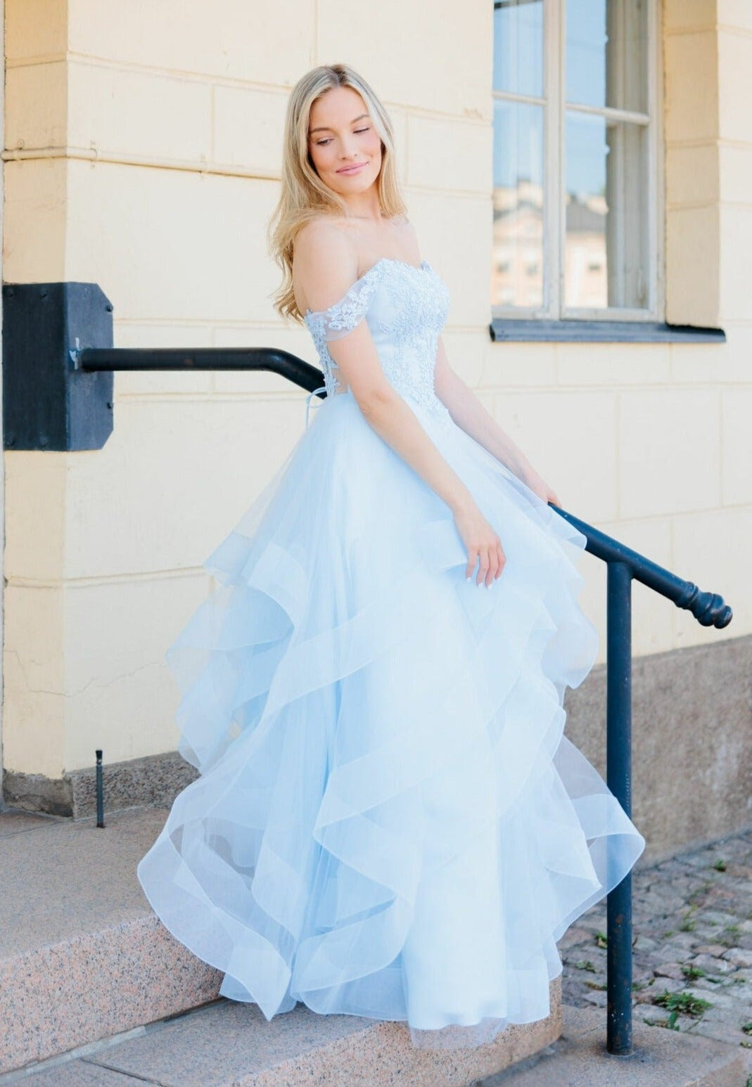 Vaaleansininen vanhojentanssimekko off-shoulder-mallilla röyhelöhelmalla.