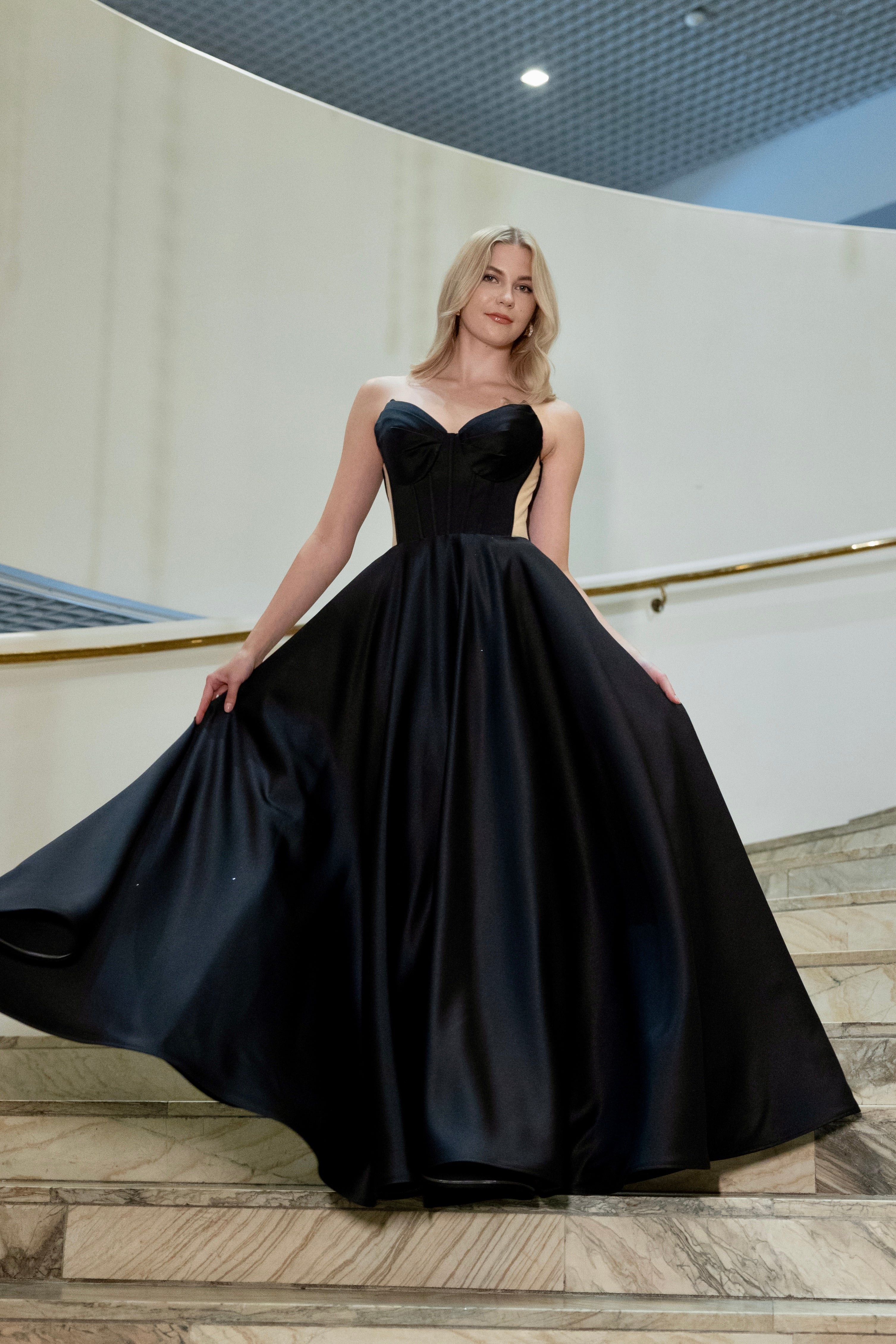 Musta vanhojentanssimekko, olkaimeton korsettiyläosa ja satiininen helma.