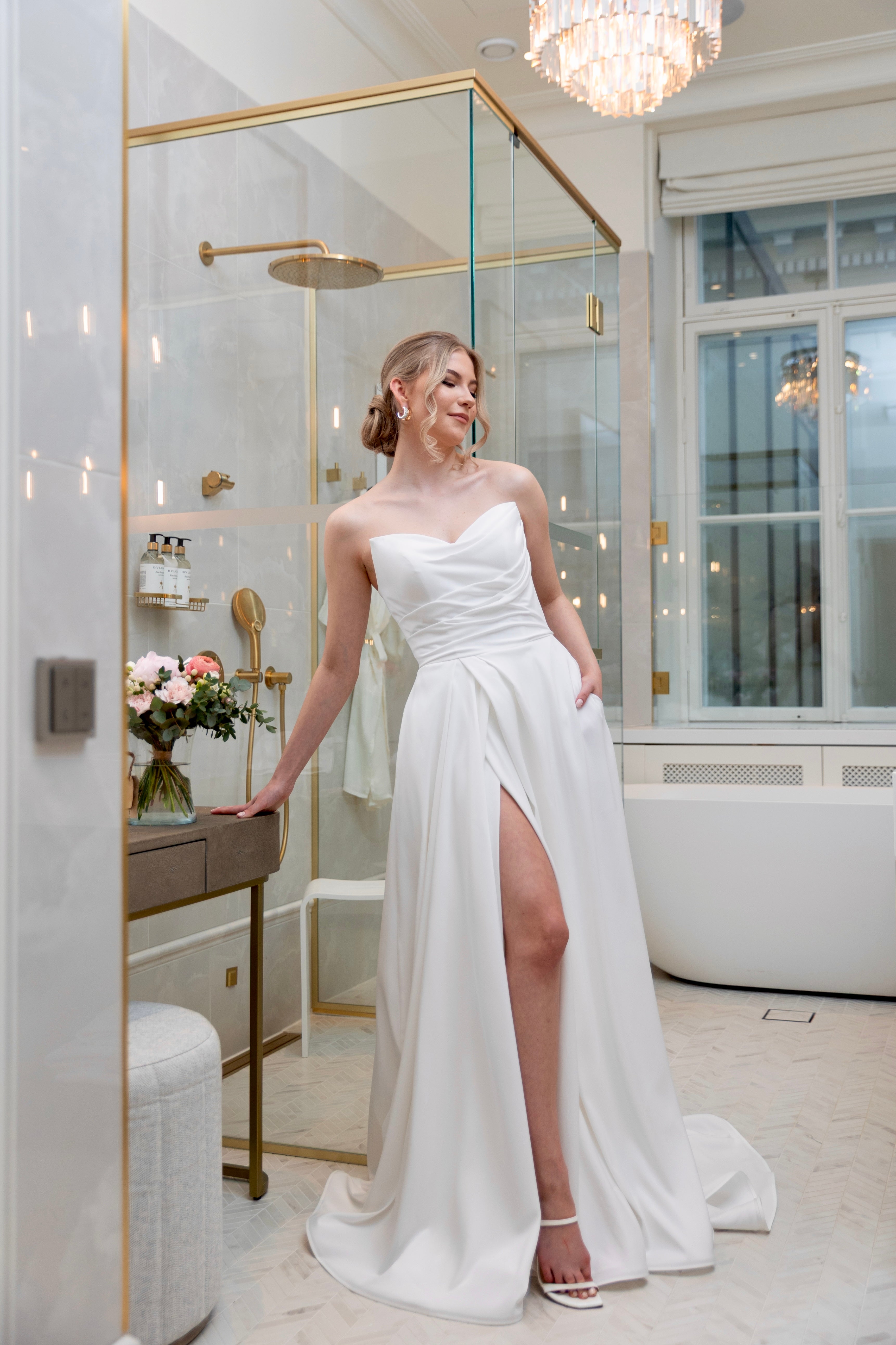 Häämekko laskeutuvalla materiaalilla ja rypytyksellä, klassinen siluetti ja moderni tyyli, edestä.