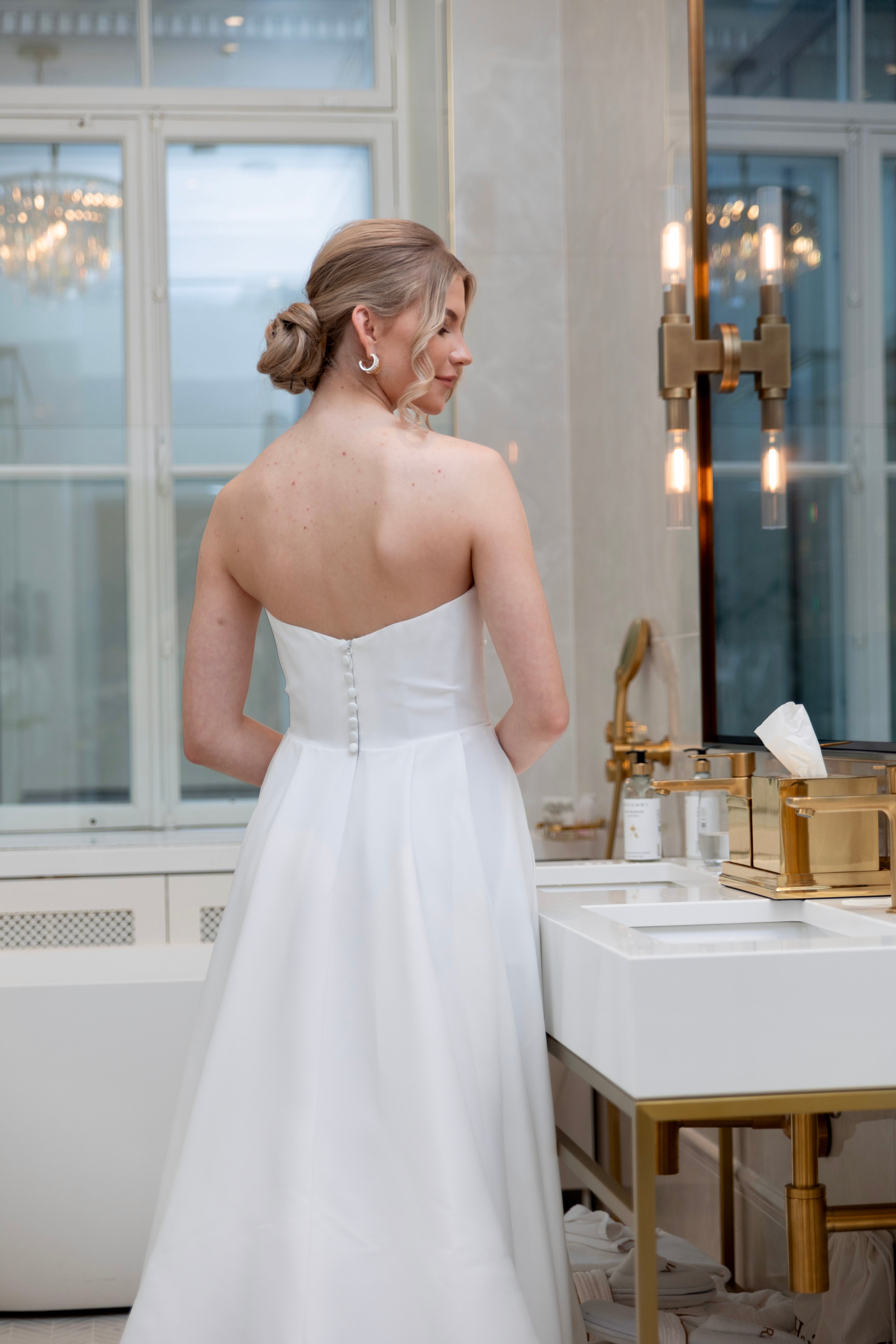 Häämekko laskeutuvalla materiaalilla ja rypytyksellä, klassinen siluetti ja moderni tyyli.