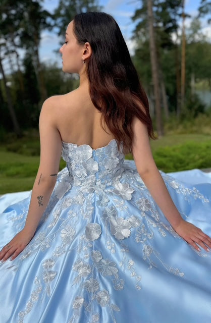 Vaaleansininen satiininen vanhojentanssimekko olkaimettomalla mallilla, koristeltu kukkapitsillä. takaa.