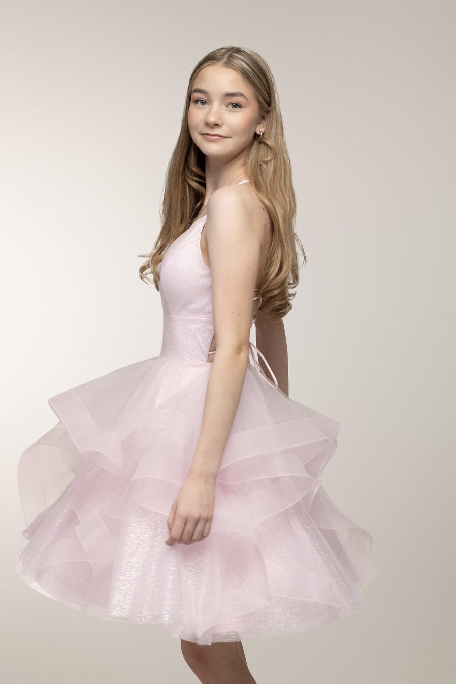 pinkki juhlamekko kimaltavasta kankaasta röyhelöhelmalla, sivusta.