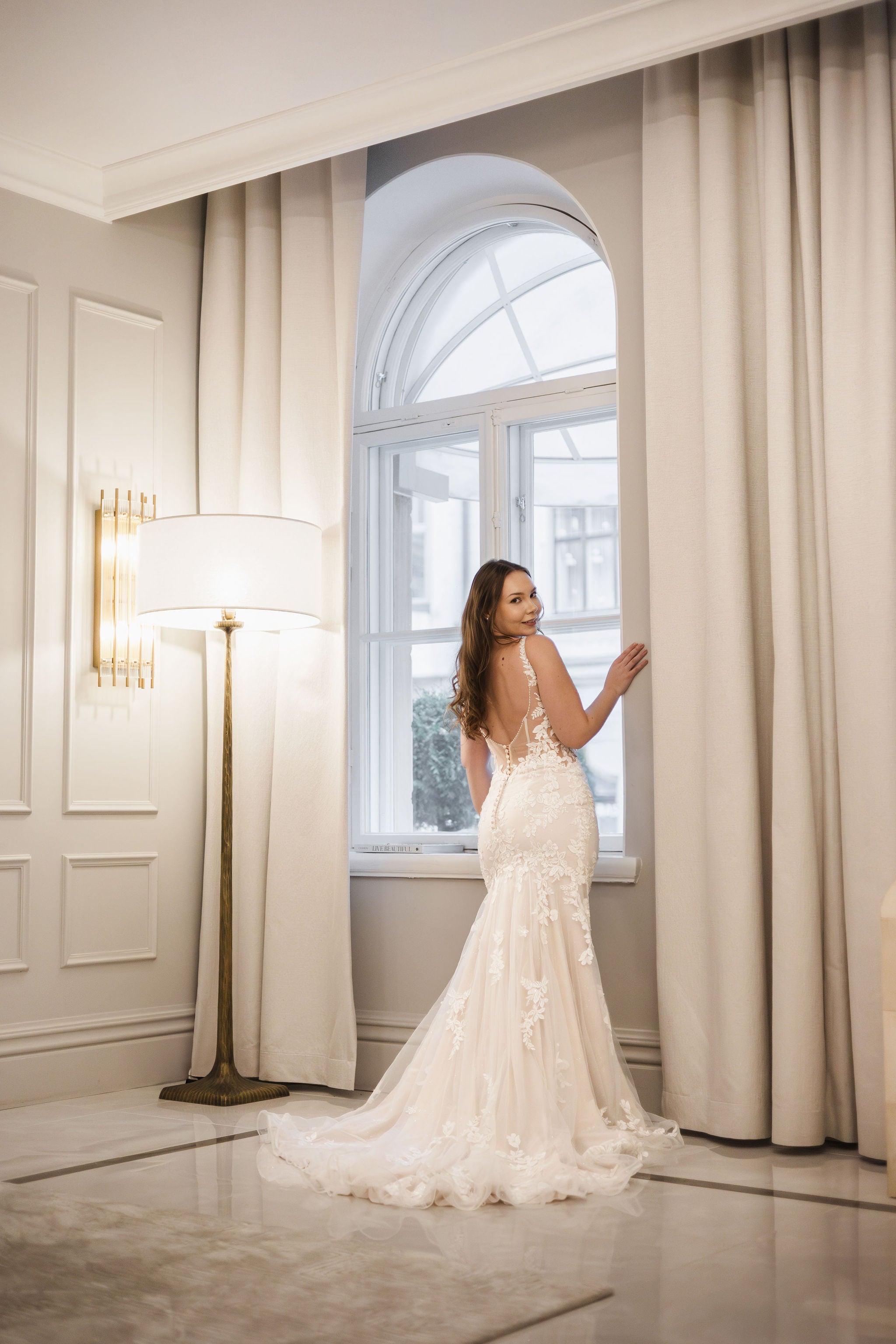 Merenneitomallinen häämekko pitsikoristeluilla, koristelluilla olkaimilla, nude pohjakankaalla ja laahuksella, takaa.